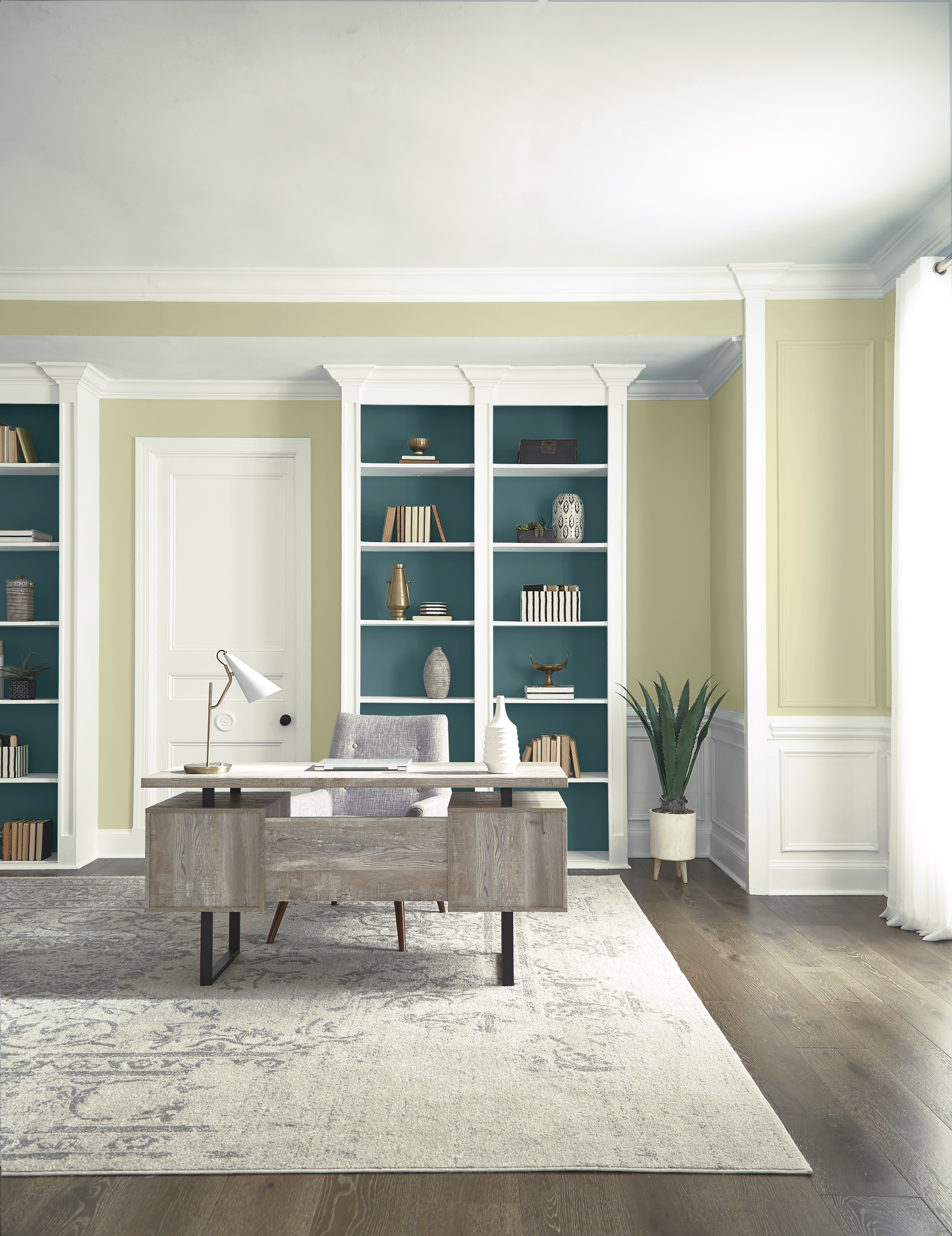 A large home office with walls in the colour Hybrid and floor-to-ceiling shelving in the colours Whisper White and Sophisticated Teal