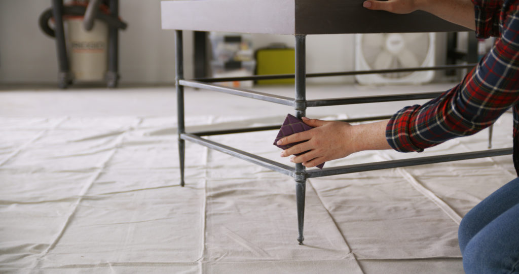 A person sanding the leg of a table