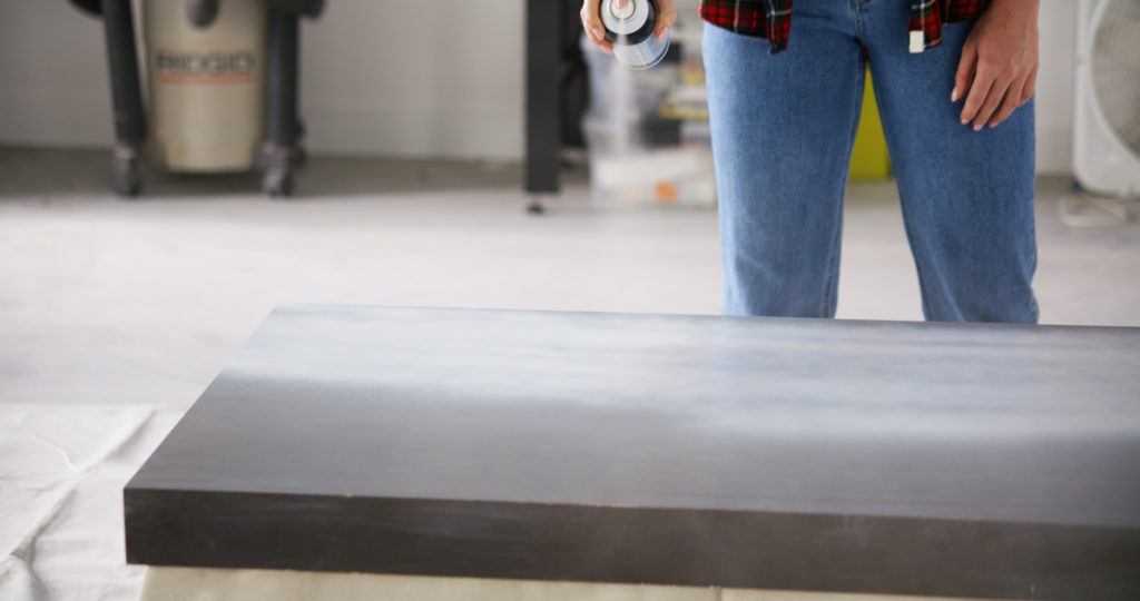 A person spray painting the top of a table