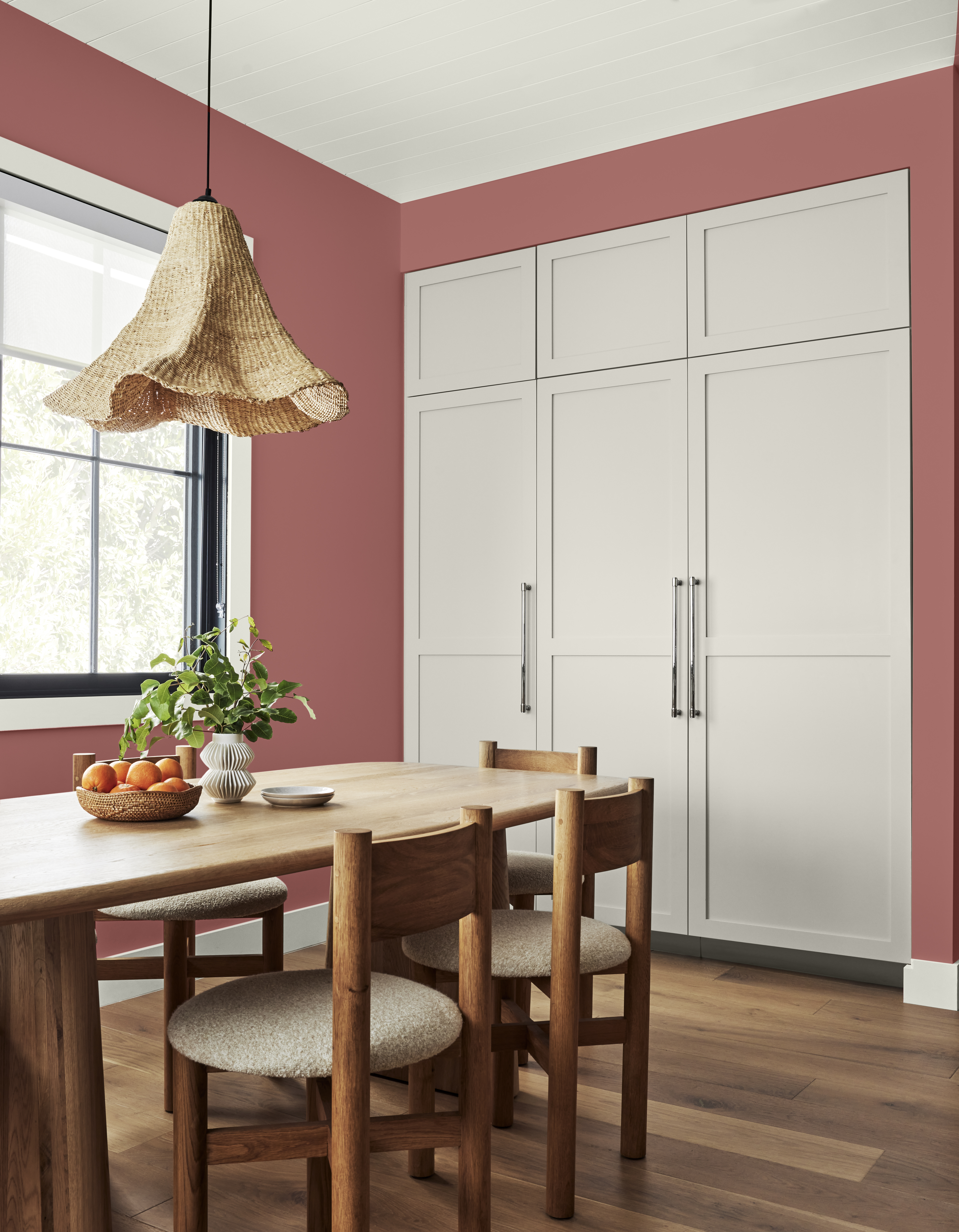 A dining room with walls in the colour Vermilion and floor-to-ceiling cabinets in the colour Gray View