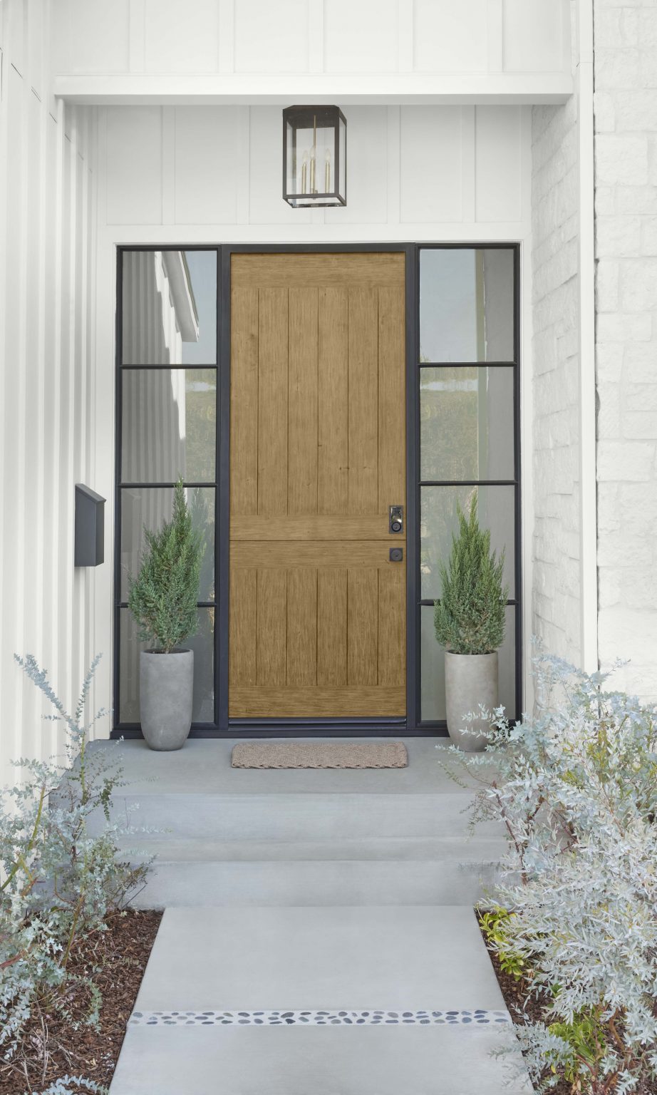 The exterior of a house with white brick and siding, and the front door stained in the colour Cedar