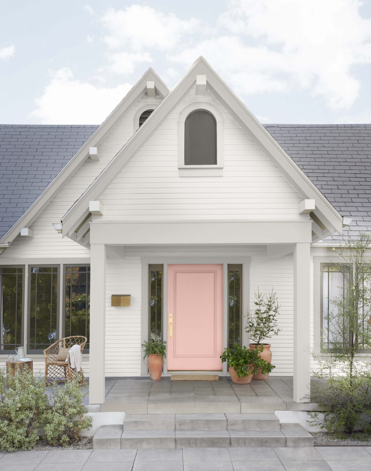 The exterior of a white house with the front door painted in the colour Prairie Rose