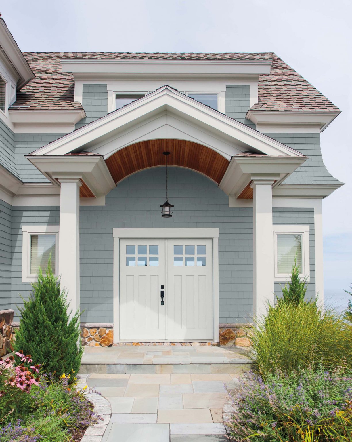 The exterior of a house with blue siding, white trim, and the front door painted in the colour Polar Bear