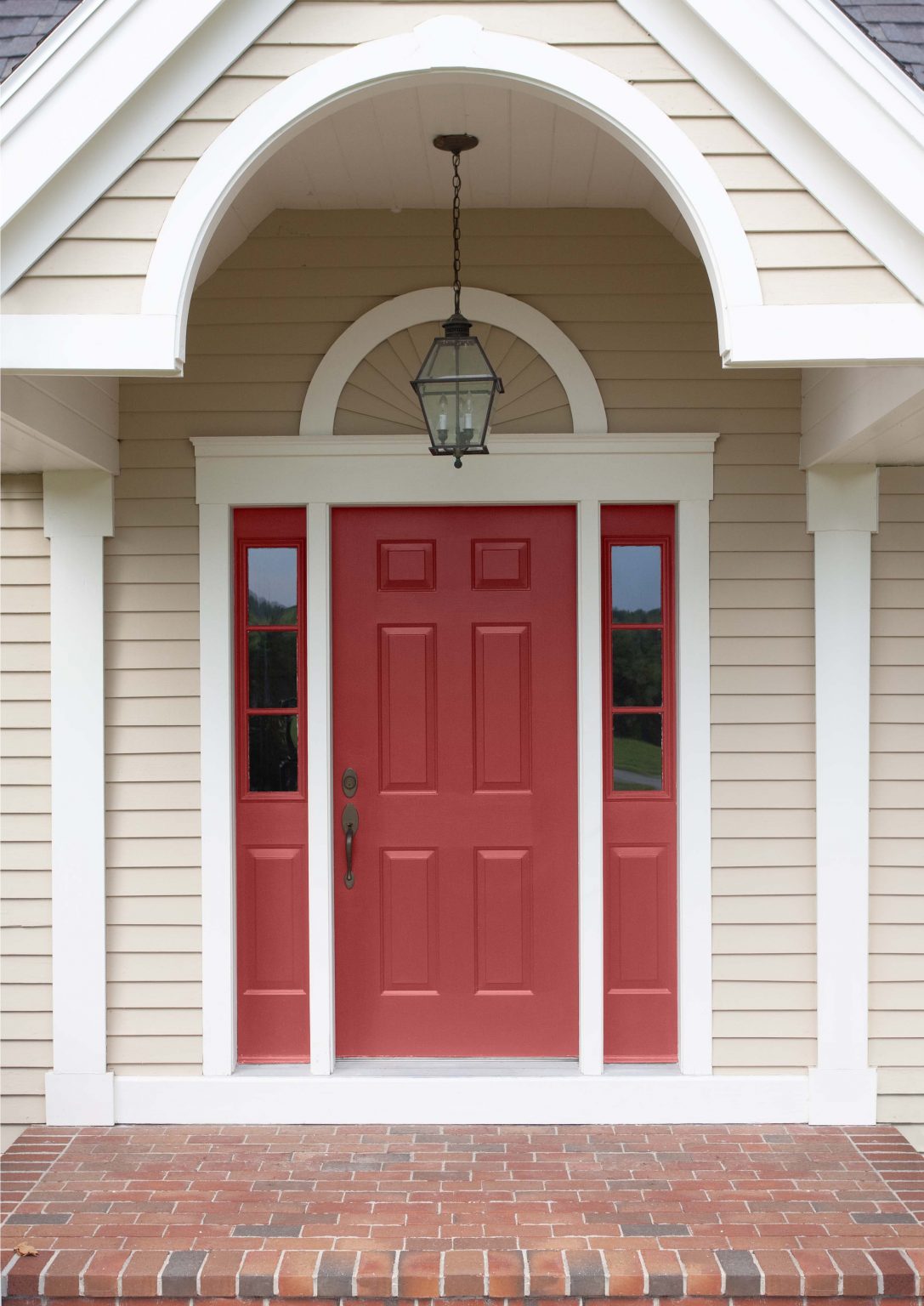 The exterior of a house with beige siding, white trim, and the front door painted in the colour No More Drama