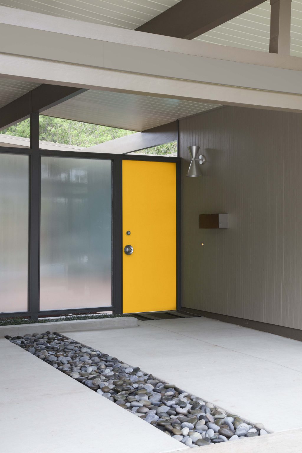 The exterior of a modern and minimalistic house with the front door painted in the colour Midsummer Gold