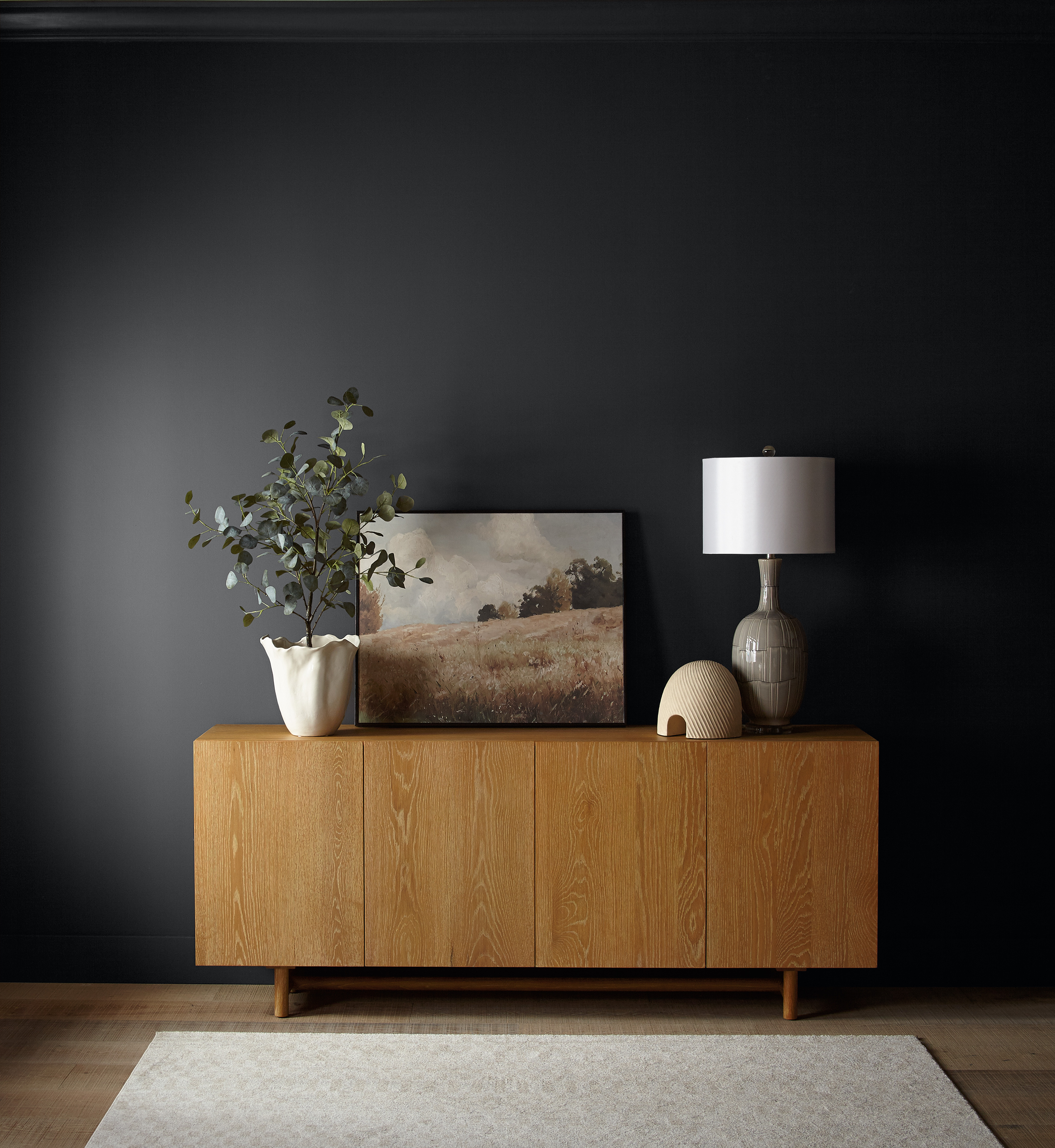 A wood sideboard styled with neutral décor, sitting against a wall in the colour Cracked Pepper