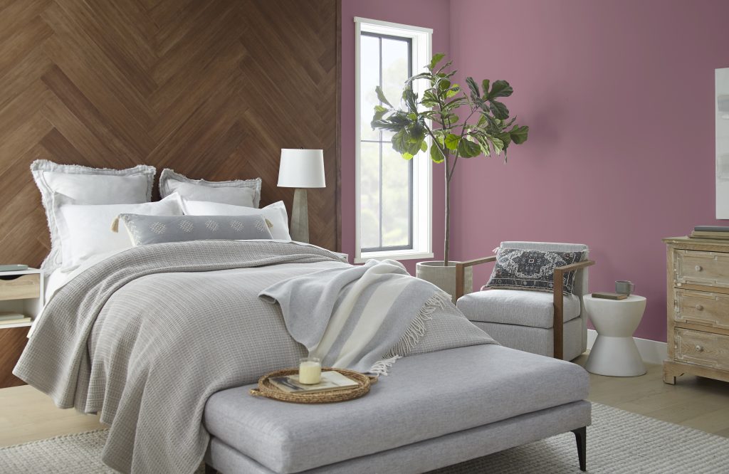 A bedroom with walls painted in the colour Full Glass, next to a floor-to-ceiling wood headboard