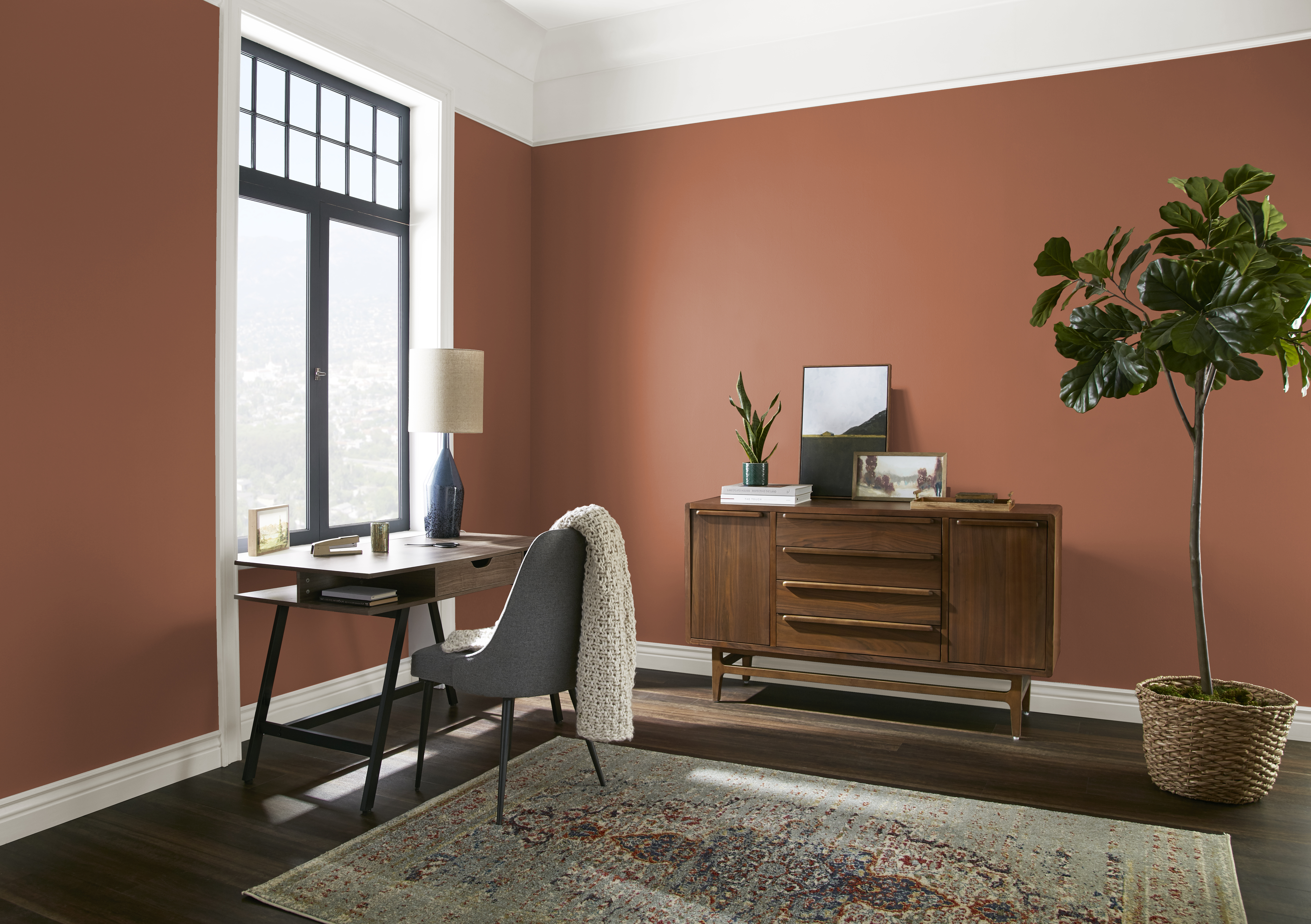 The corner of a room with walls in the colour Orange Flame and styled with neutral mid-century modern furniture
