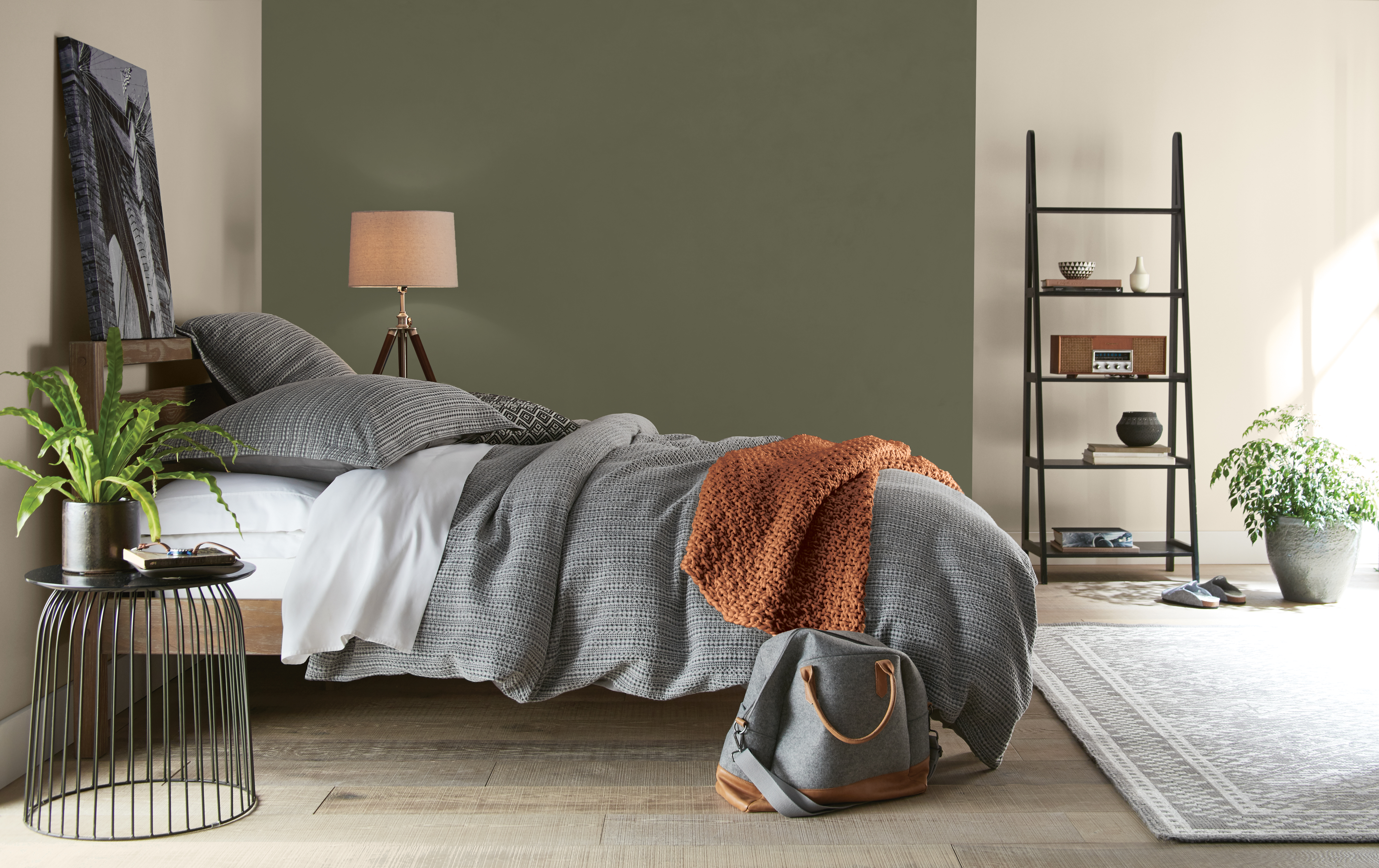 A bedroom with walls in the colour Even Better Beige and an accent wall in the colour Mountain Olive next to the bed