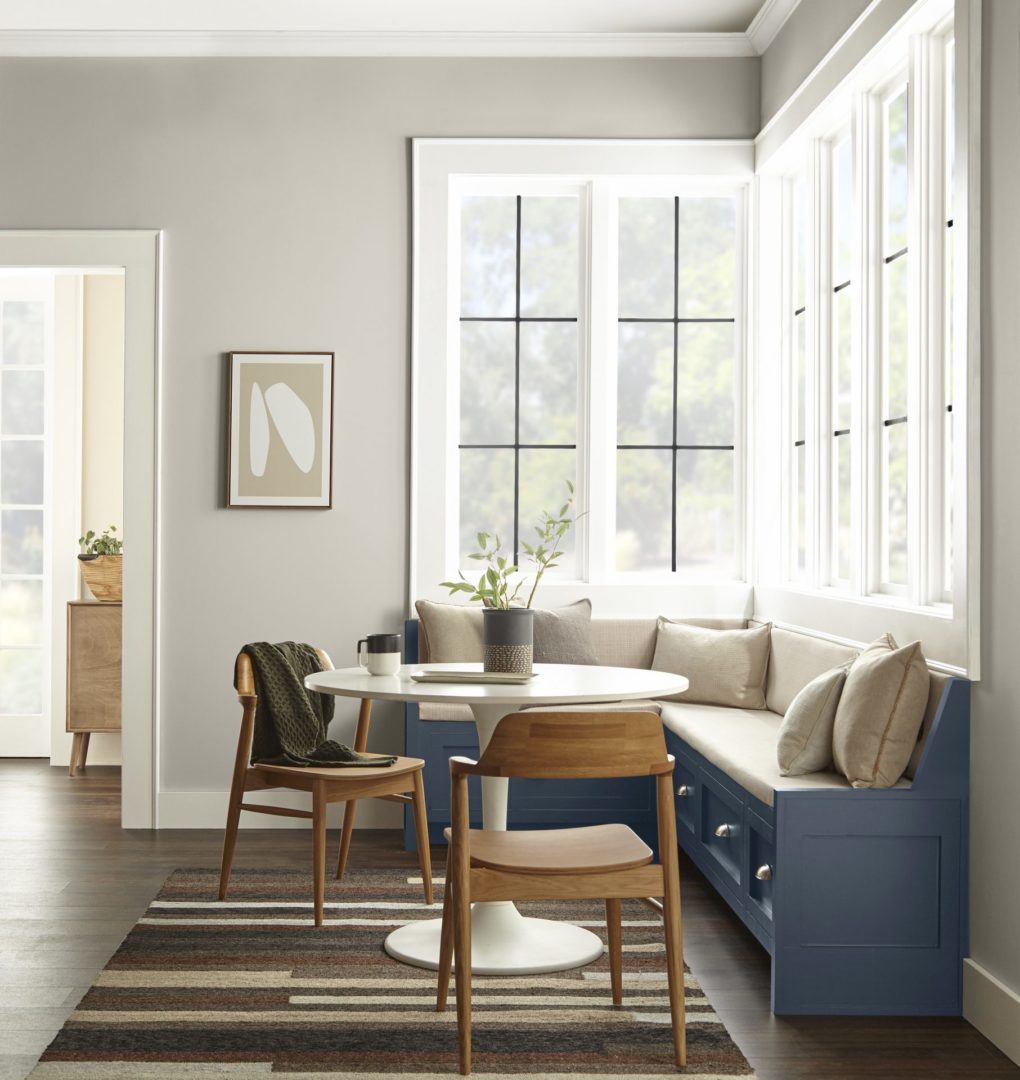 A farmhouse-style breakfast nook with large windows, neutral walls, and a dark blue wooden sitting area