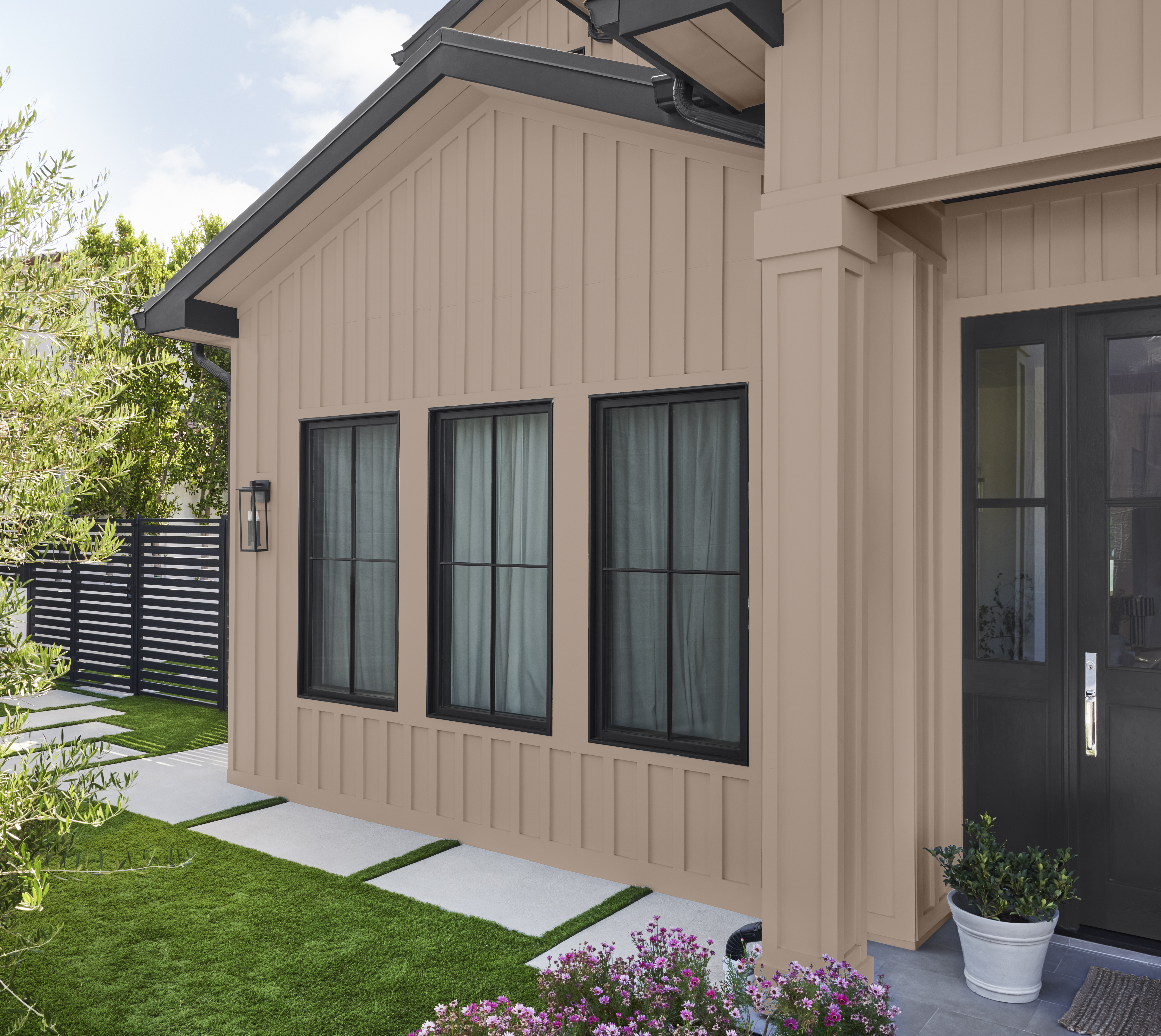 The exterior of a house with taupe siding and black trim 