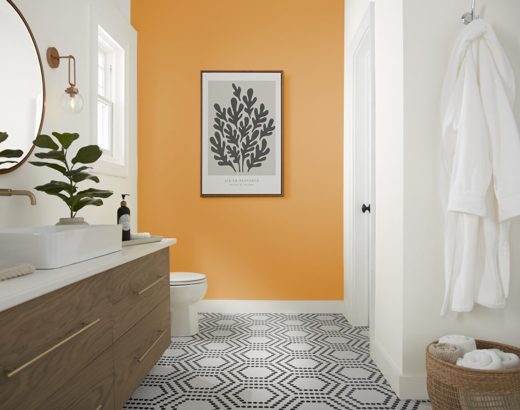 A modern bathroom with a cheerful yellow accent wall and a black and white geometric tiled floor 
