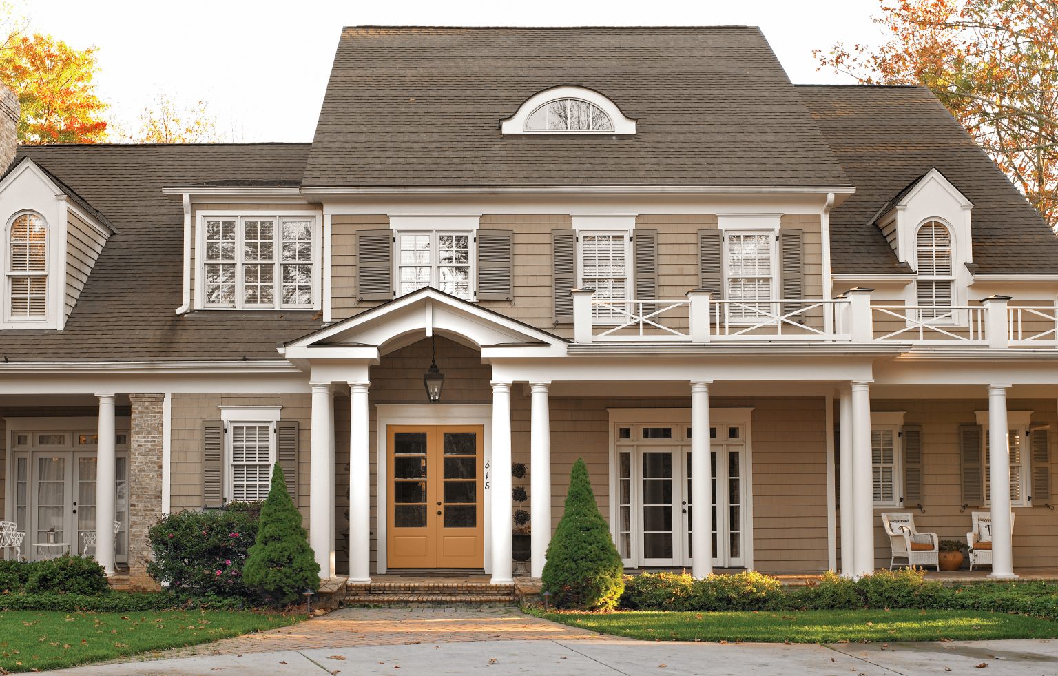 The exterior of a home painted in a brown colour with the door in a golden orange-yellow hue