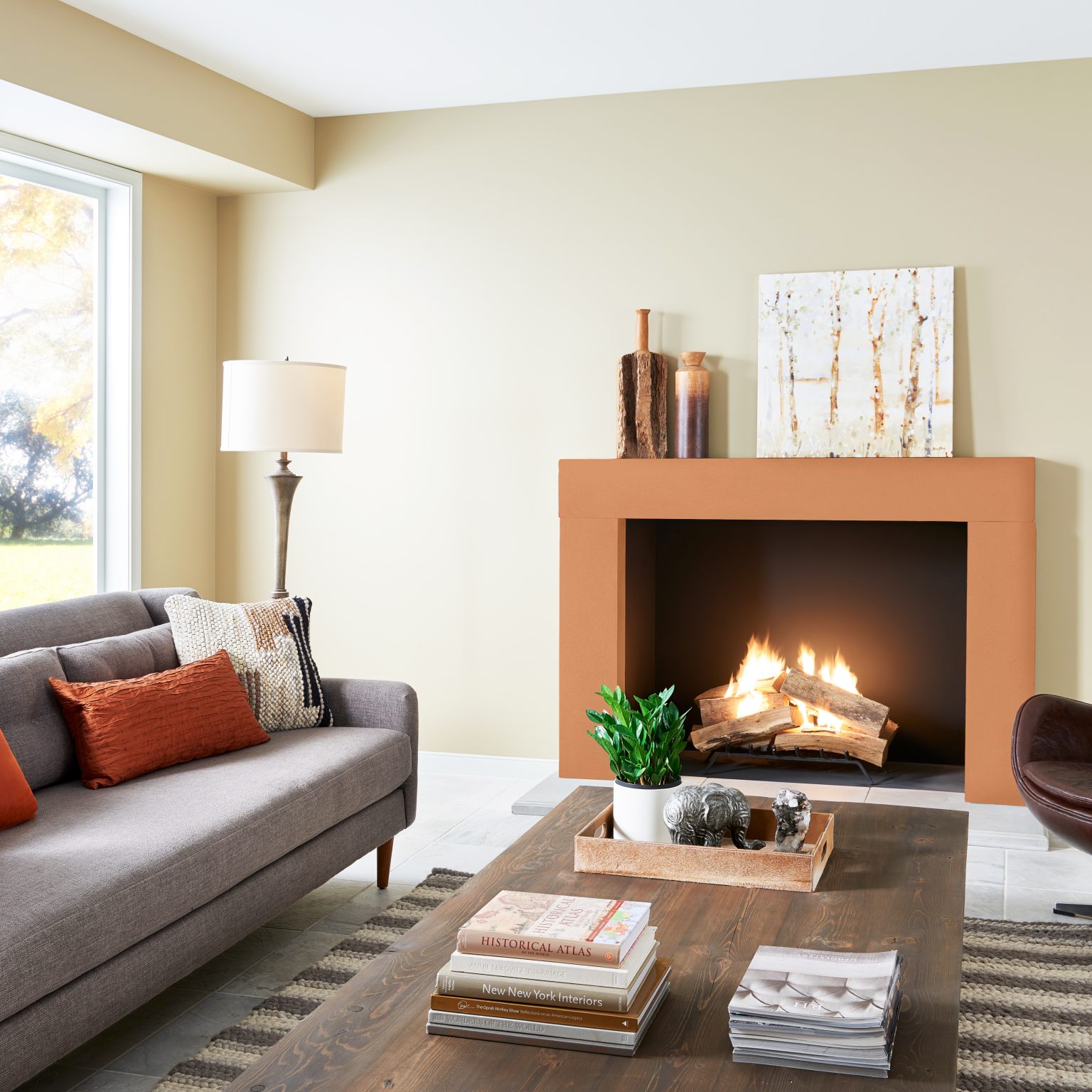 A living room with walls in a neutral-yellow hue and the fireplace in the colour Blazing Autumn