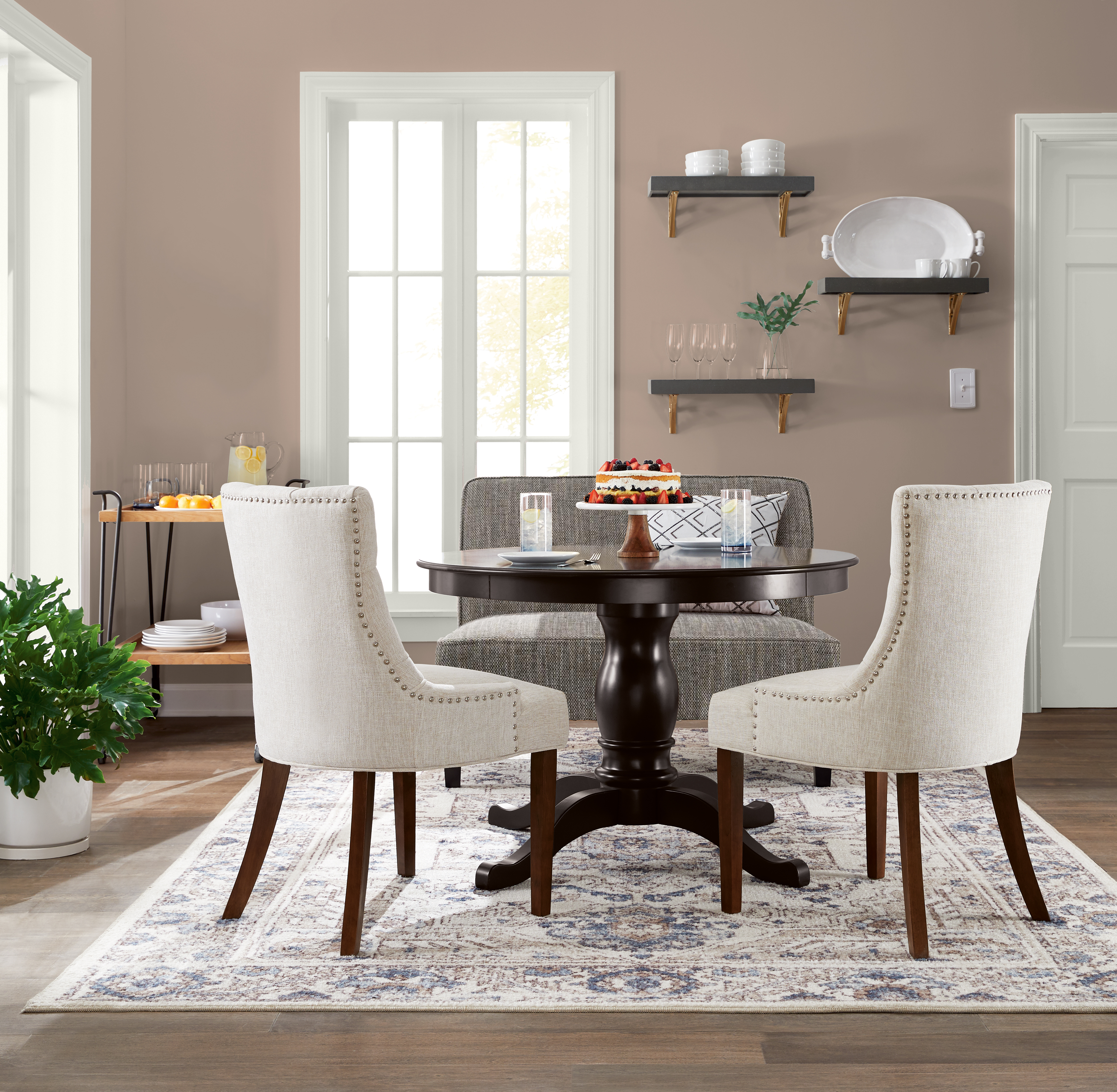 A dining area with taupe walls and white trim around the windows and doors