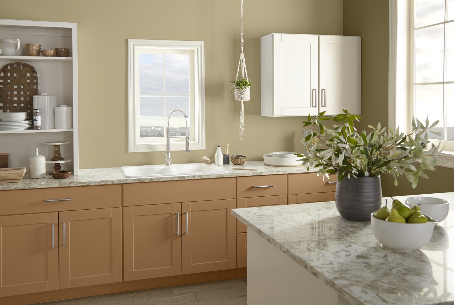 A kitchen with walls painted in an earthy green, styled with plants and minimalist dishware and décor
