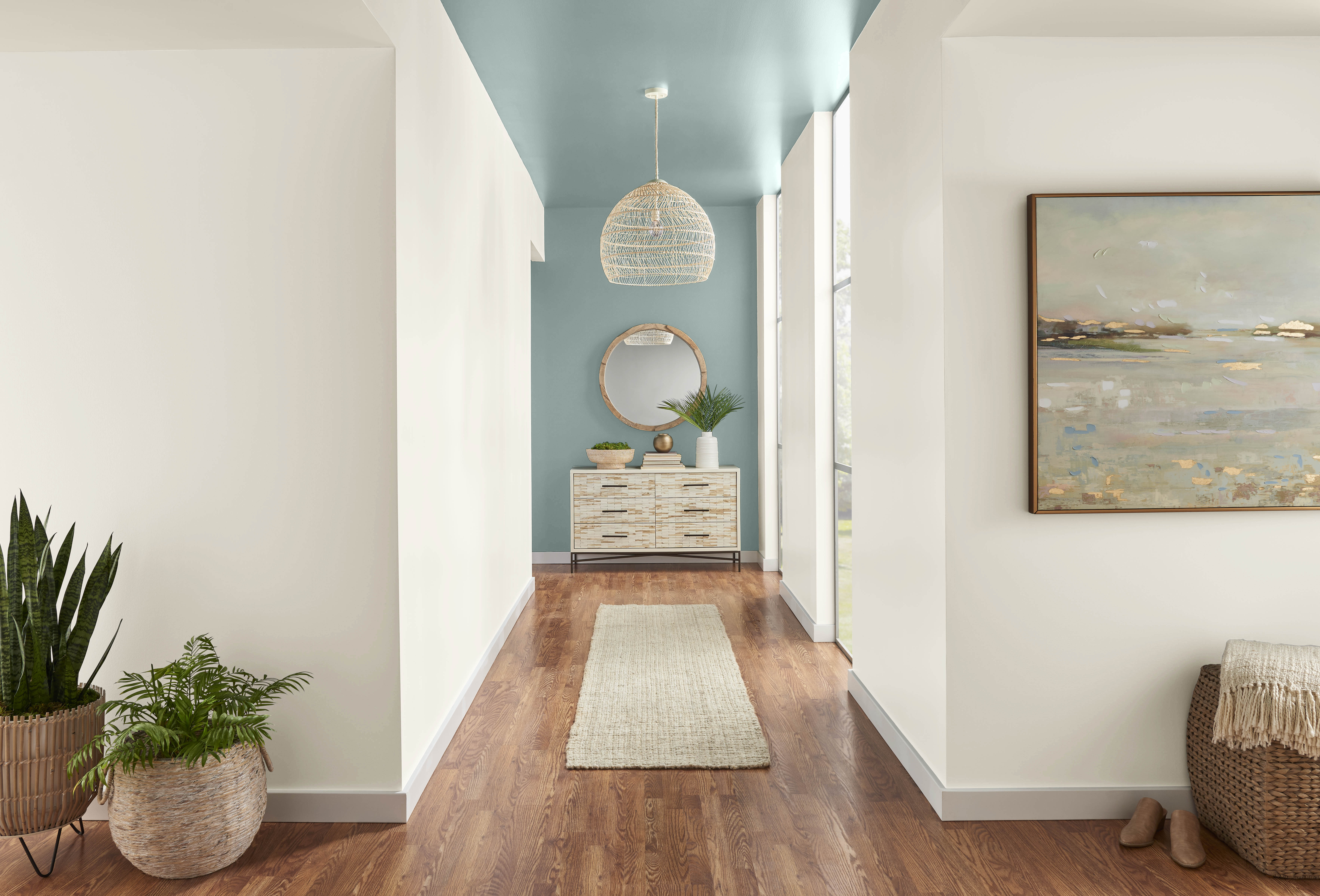 A long hallway with white walls and an accent wall and ceiling painted in a dusty blue green colour