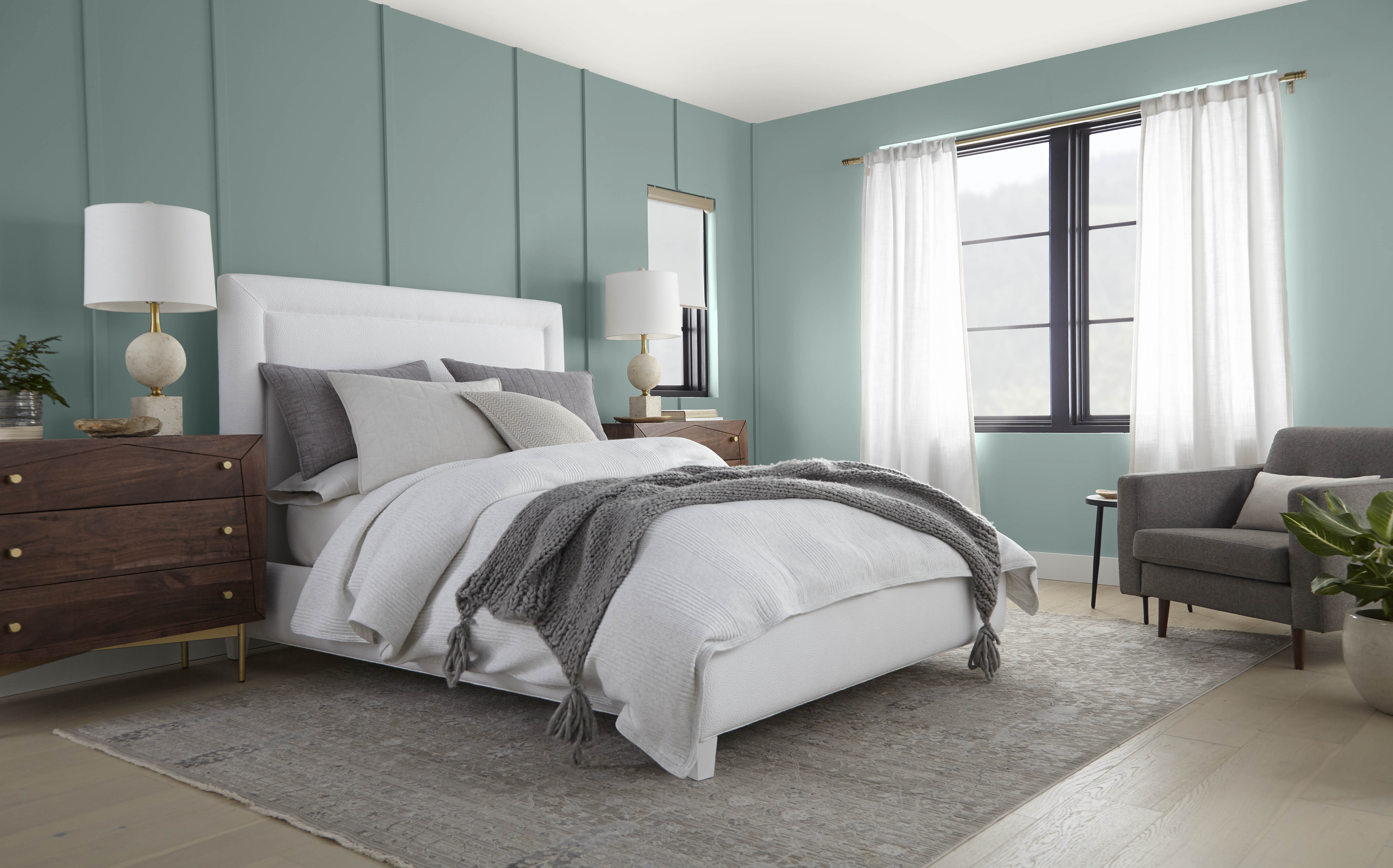 A bedroom with panelled walls painted in a dusty blue green colour