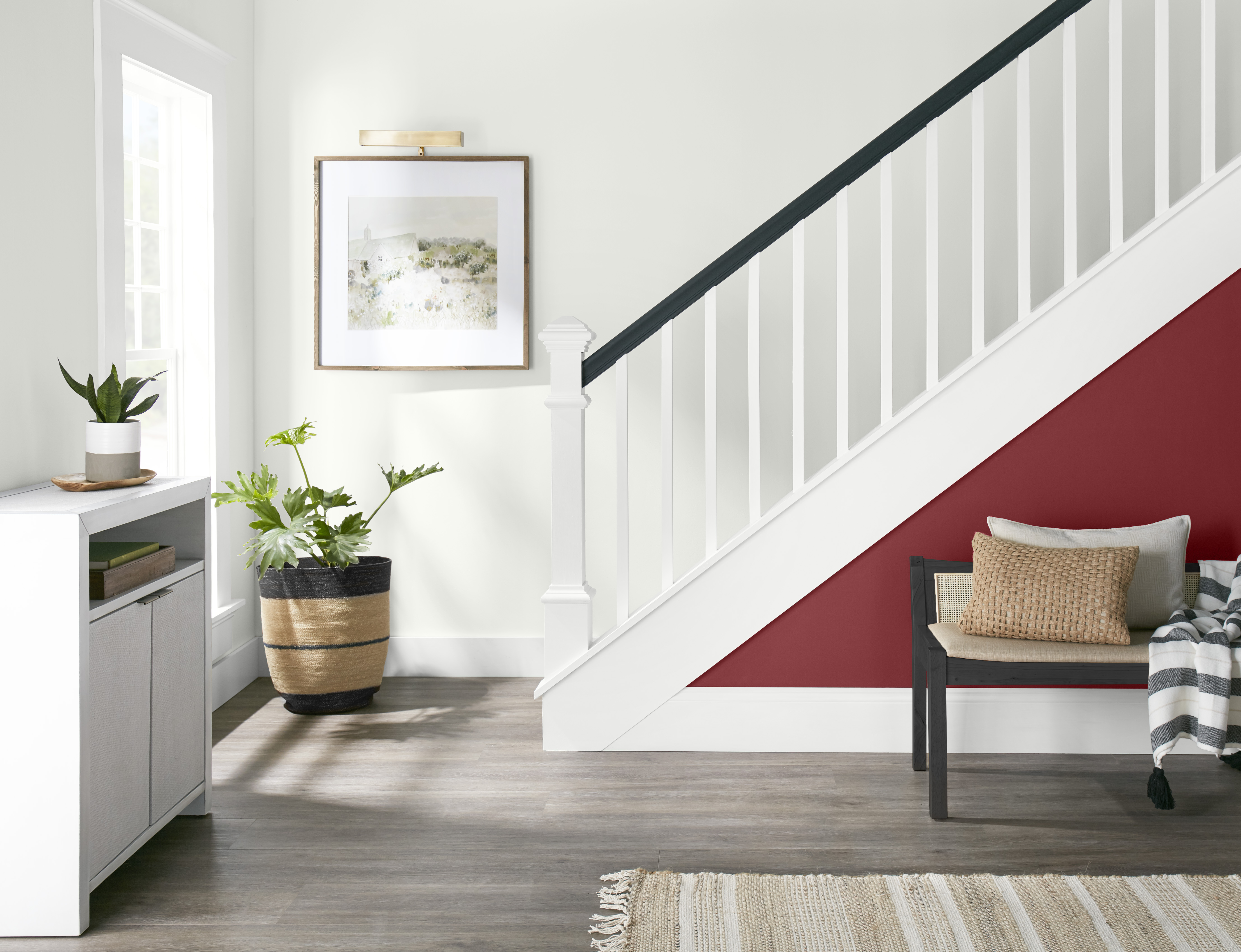 A bright white entry area with the side of the staircase painted in a deep red colour