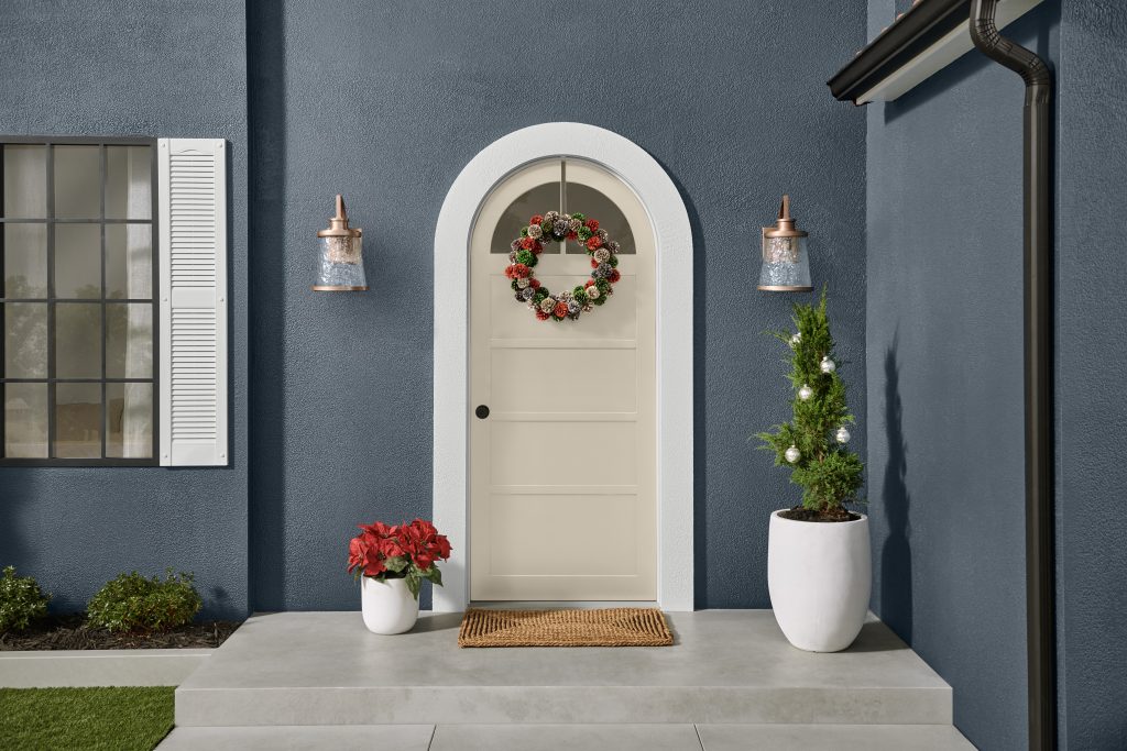 The exterior of a house with the doorway decorated with a pinecone wreath and holiday décor