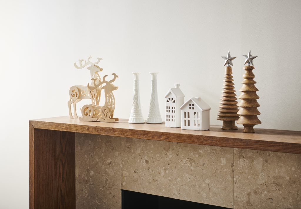A fireplace mantle with holiday decorations before being spray painted