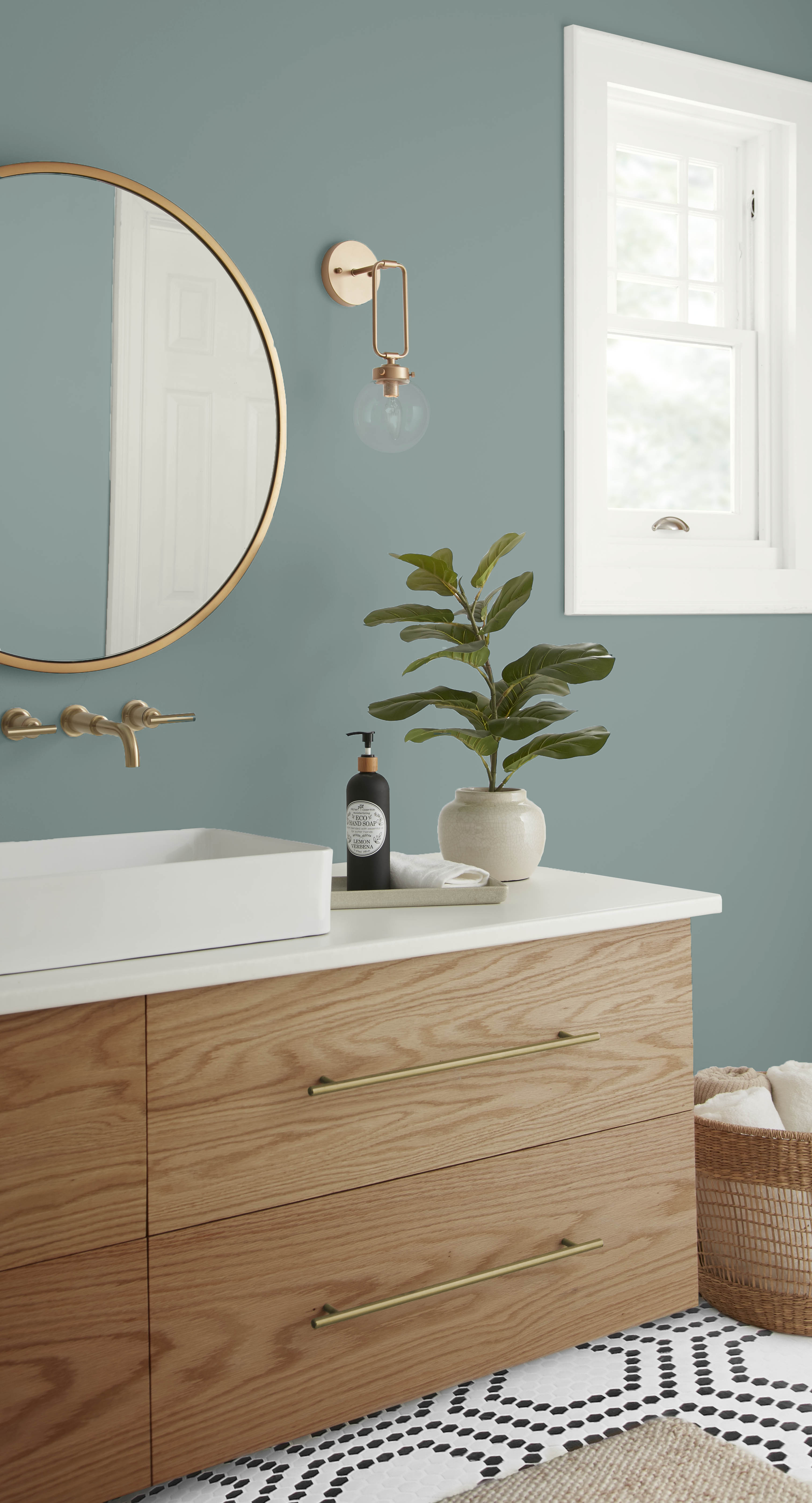 A closeup of a Scandinavian-style bathroom with walls painted in a dusty blue green colour