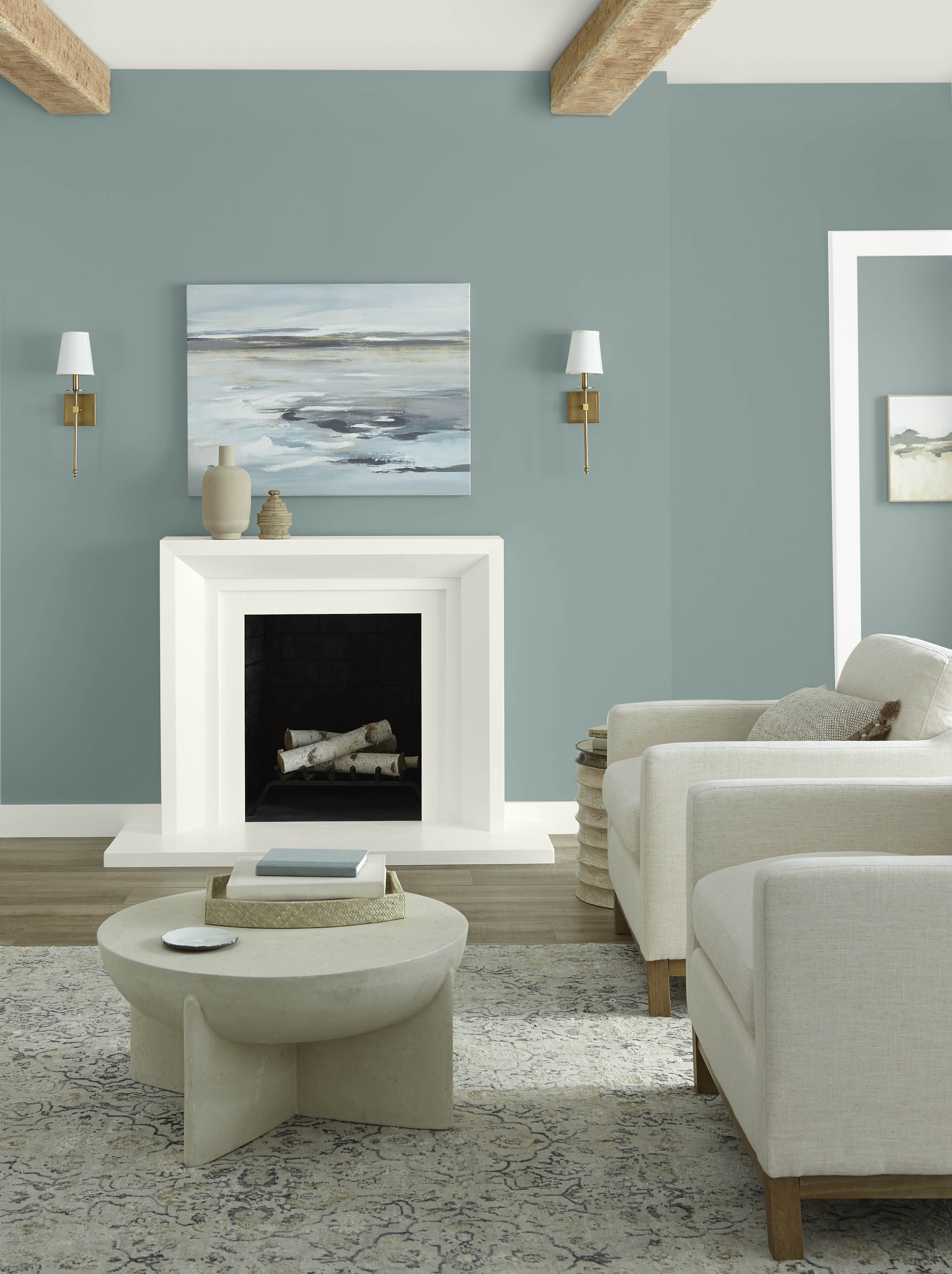 A living room with walls painted in a dusty blue green colour and white trim, ceiling, and fireplace