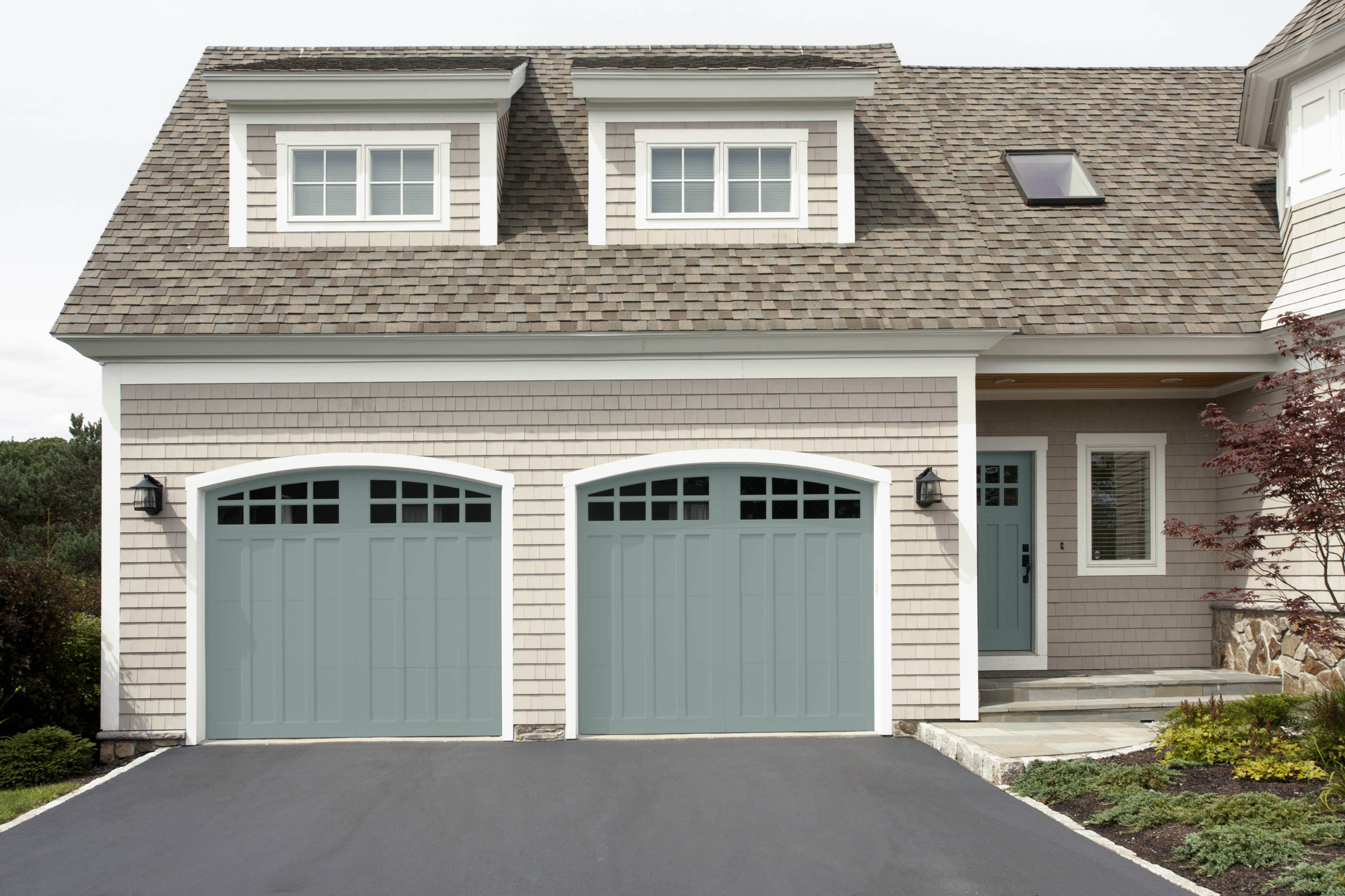 The exterior of a house with the front door and garage doors painted in a dusty blue green colour