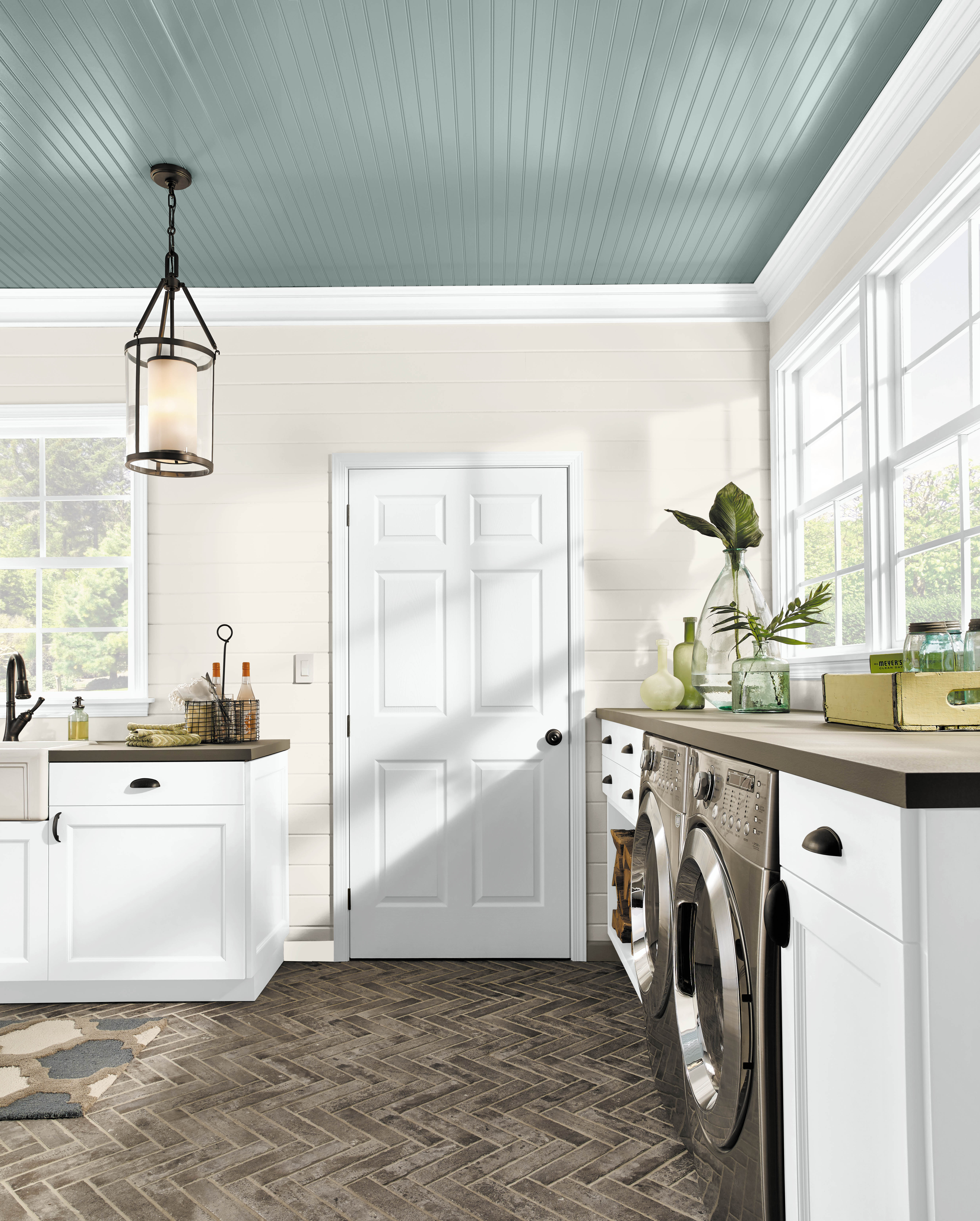 A bright and spacious laundry room with white walls and the ceiling painted in a dusty blue green colour
