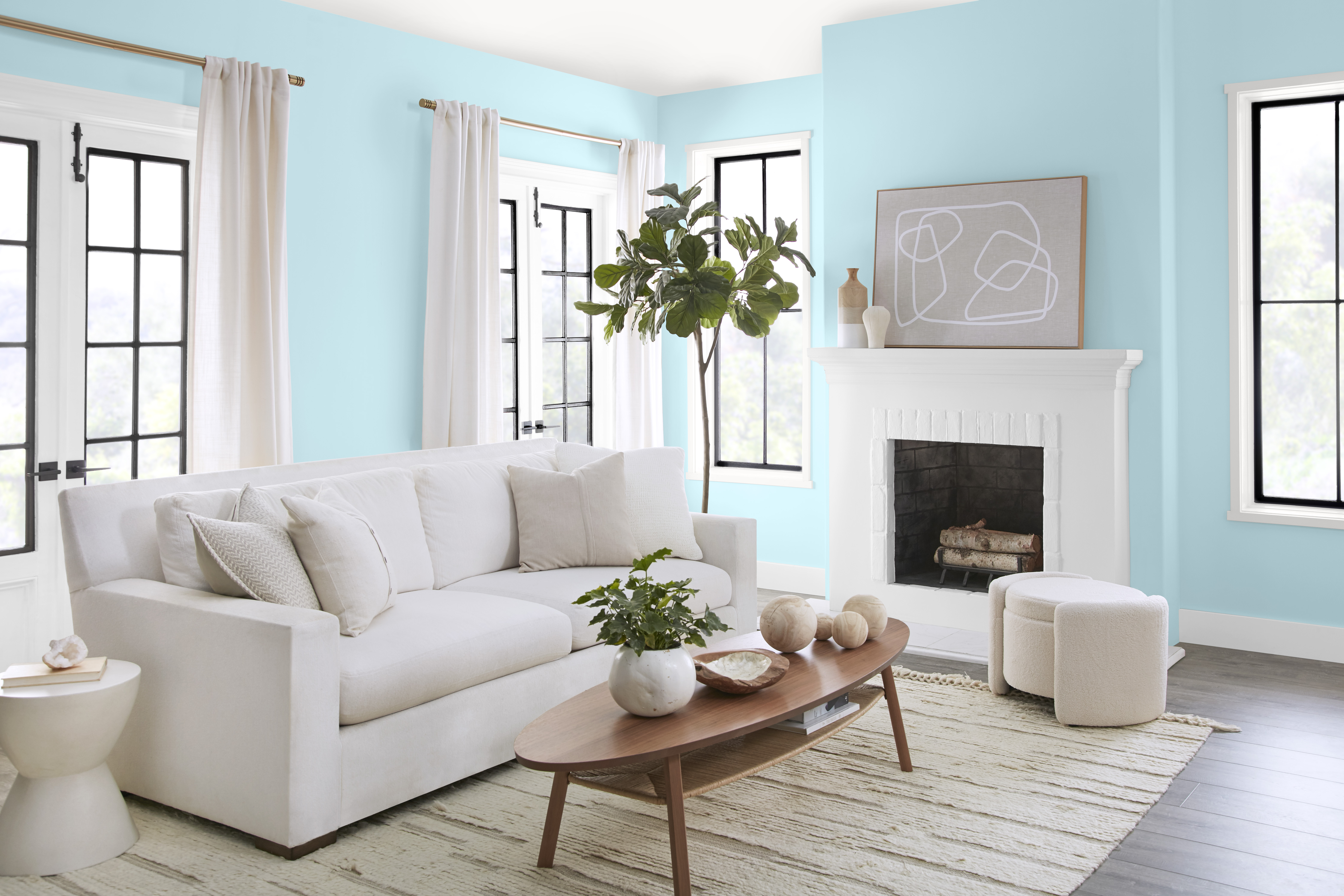 A bright living room with walls painted in a light blue colour, styled with white and neutral furniture and décor