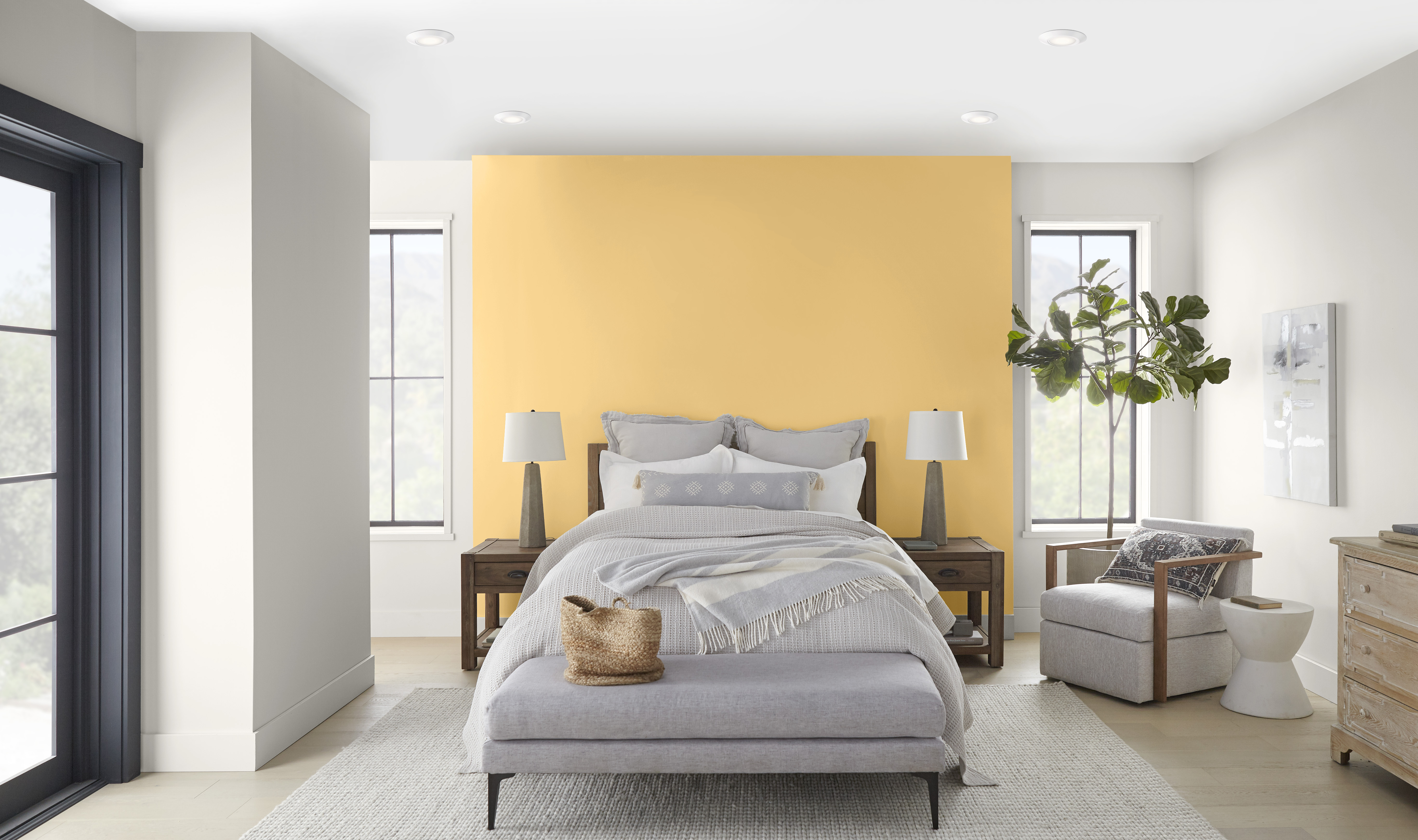 A light-filled bedroom with the bed headboard wall painted in a bright mustard colour