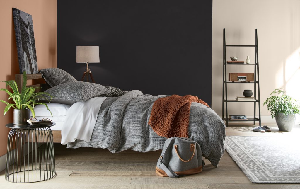 A bedroom with walls painted in different colours – a terracotta tone, black, and a light neutral colour
