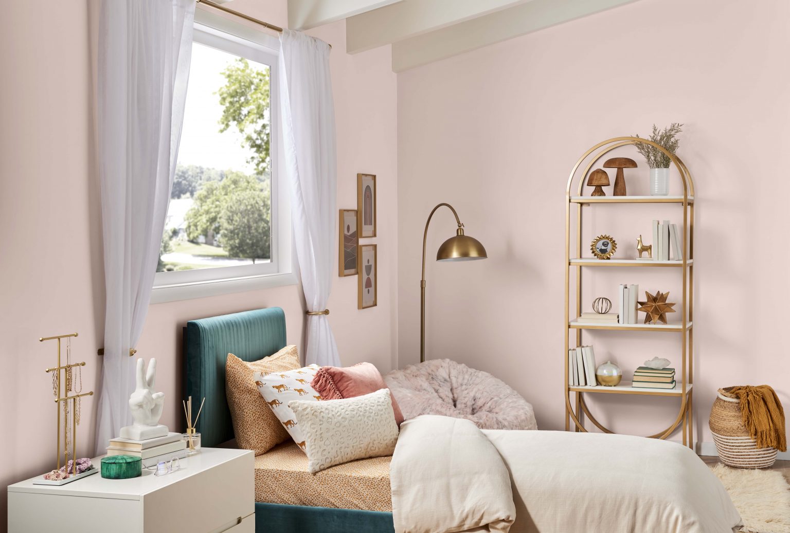 A teen bedroom with walls painted in a neutral light pink colour, styled with neutral and metallic gold décor accents 