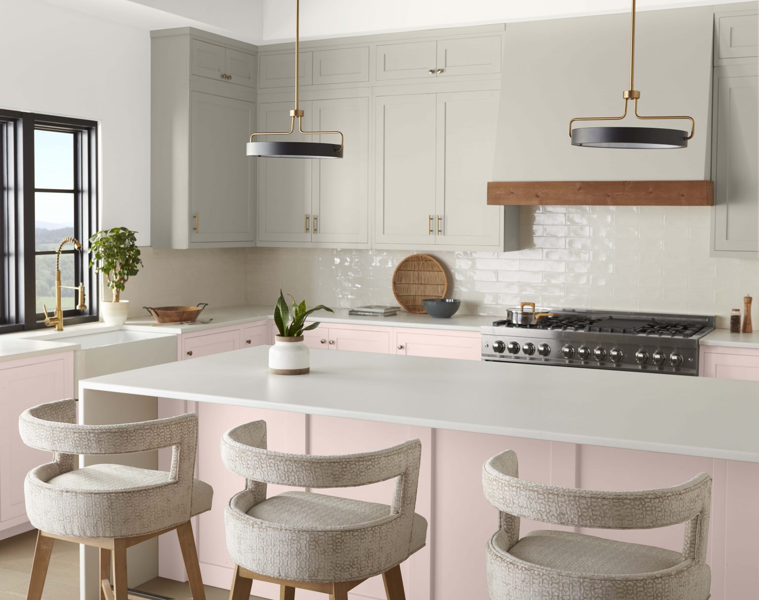 A contemporary kitchen with upper cabinets painted in a light grey colour and bottom cabinets and the island painted in a neutral light pink colour  