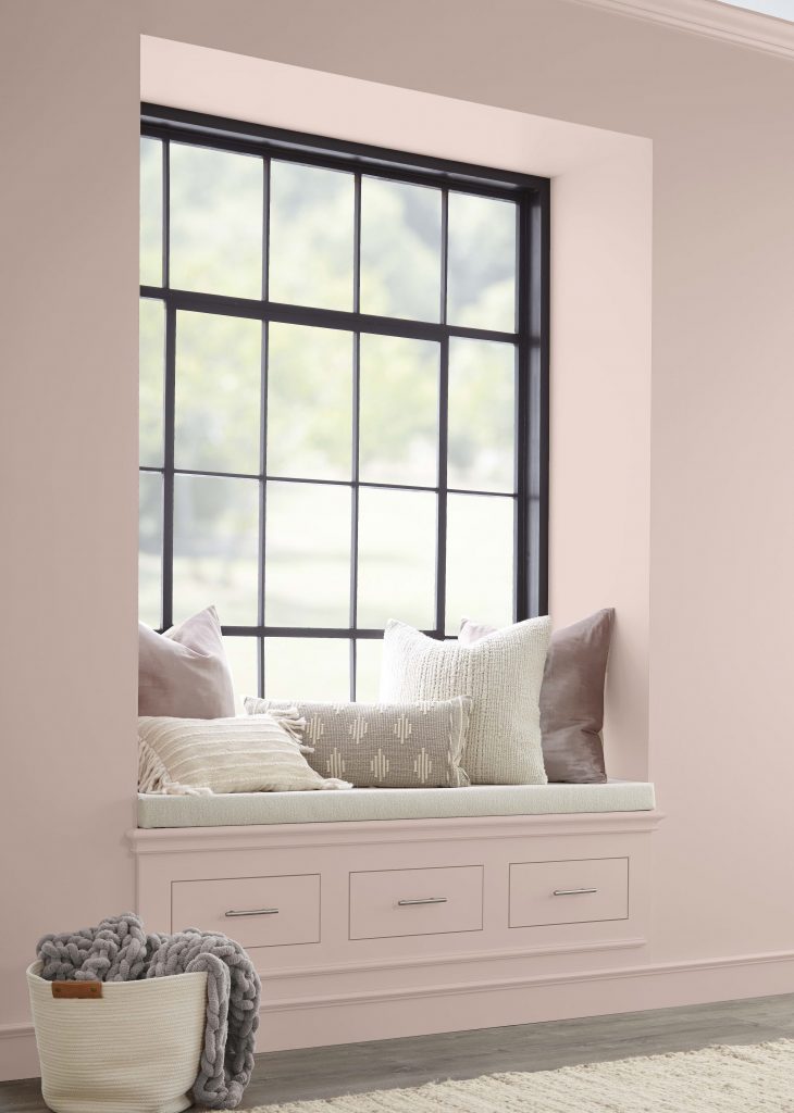 A reading nook with walls and cabinets painted in a neutral light pink colour