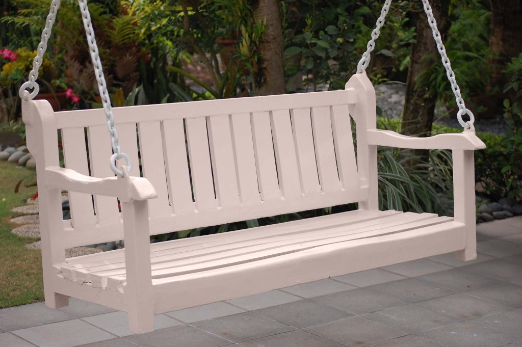 An outdoor bench swing painted in a neutral light pink colour