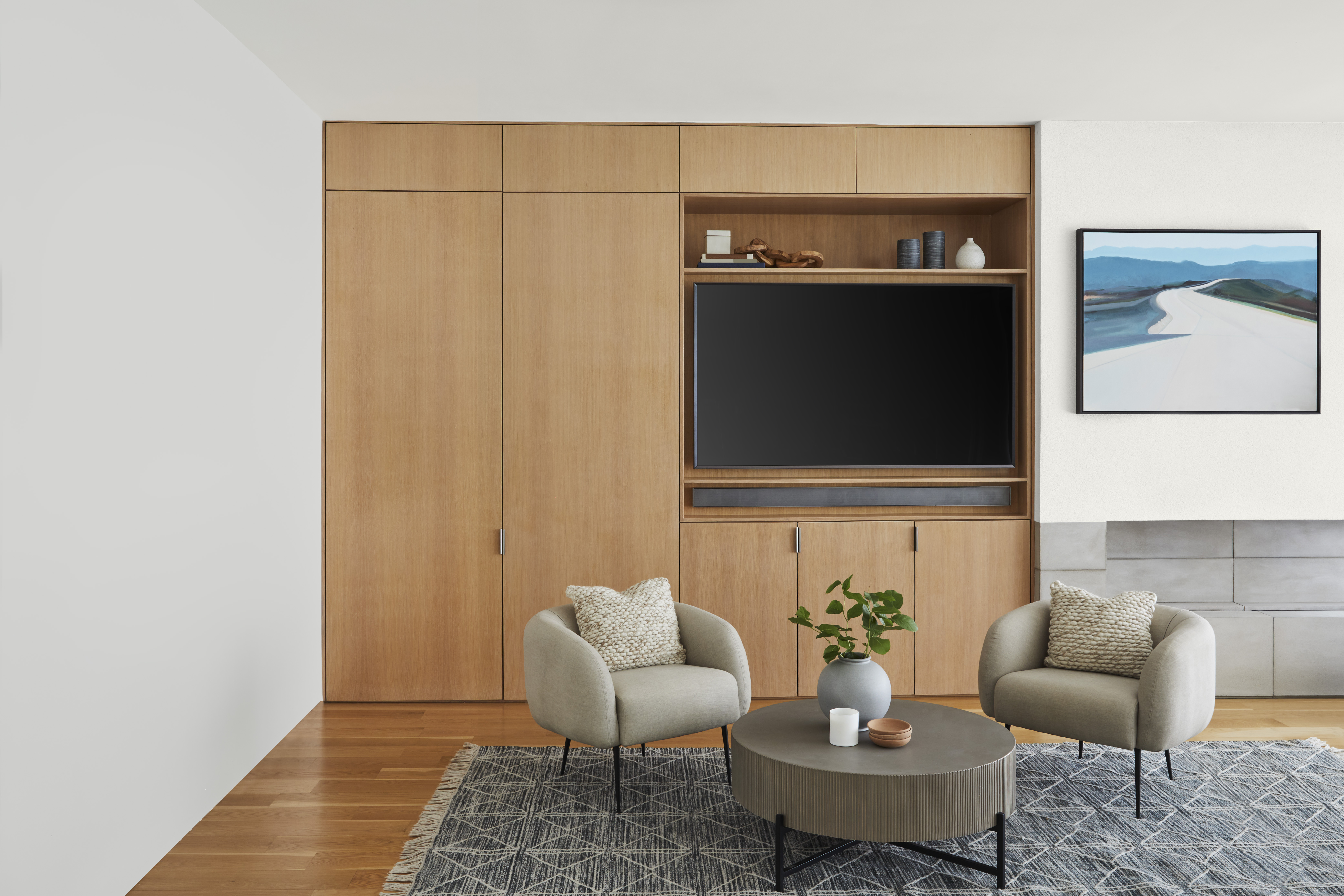 A living room with white walls and a built-in wood media unit and cabinets
