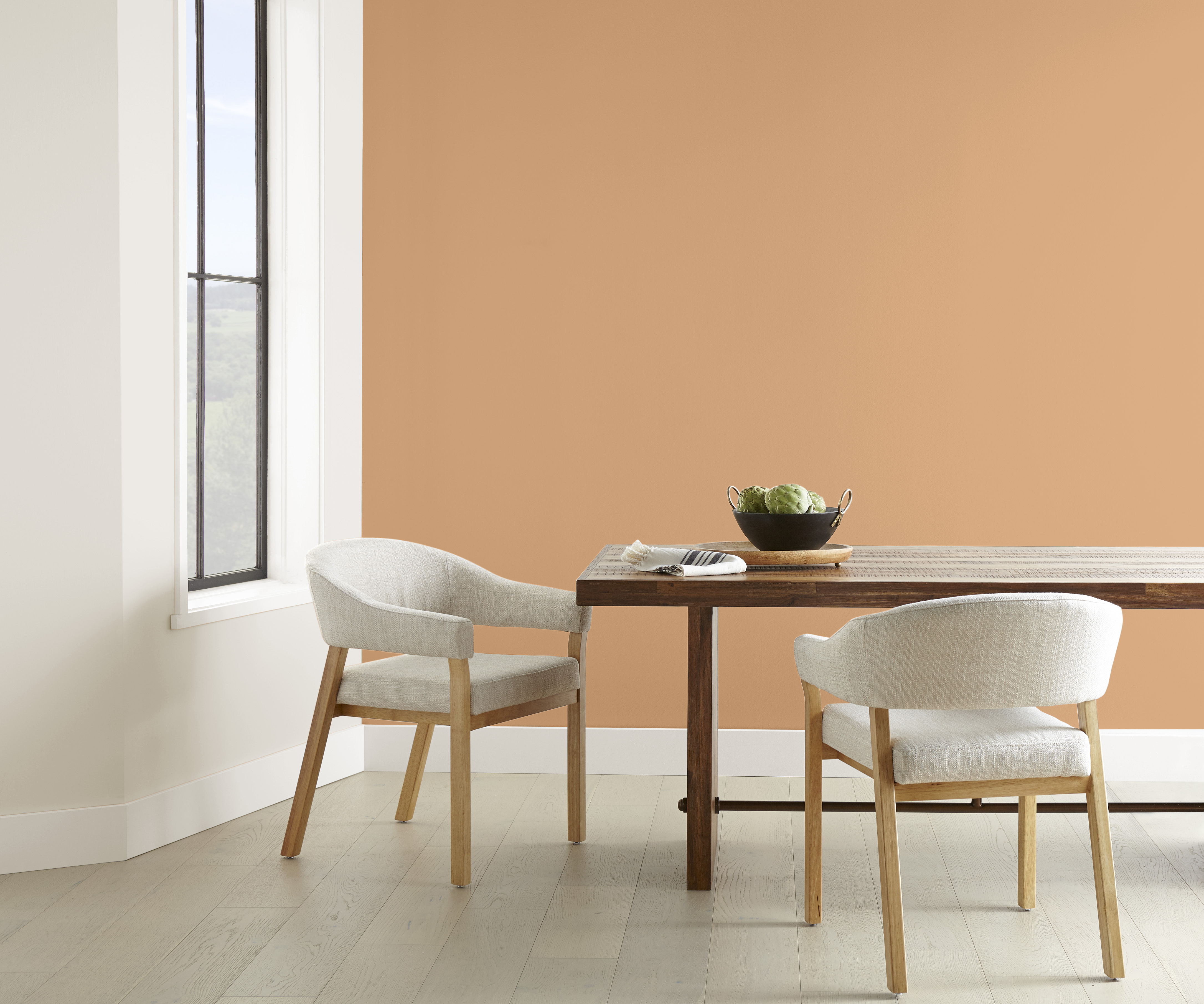 A minimalistic dining space with an accent wall painted in a light golden-brown colour
