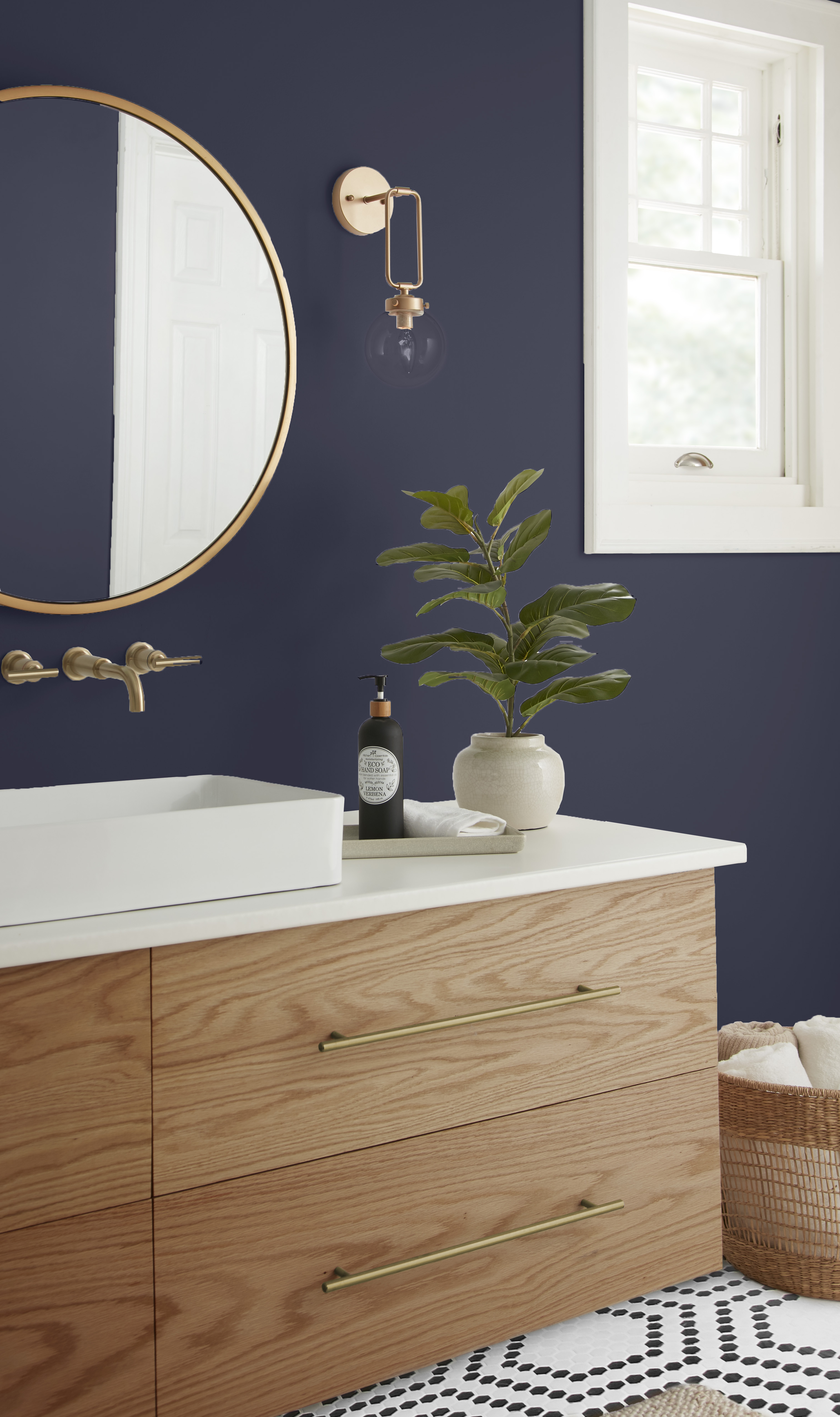 A closeup of a bathroom vanity with light wood cabinets, with walls painted in a deep blue colour