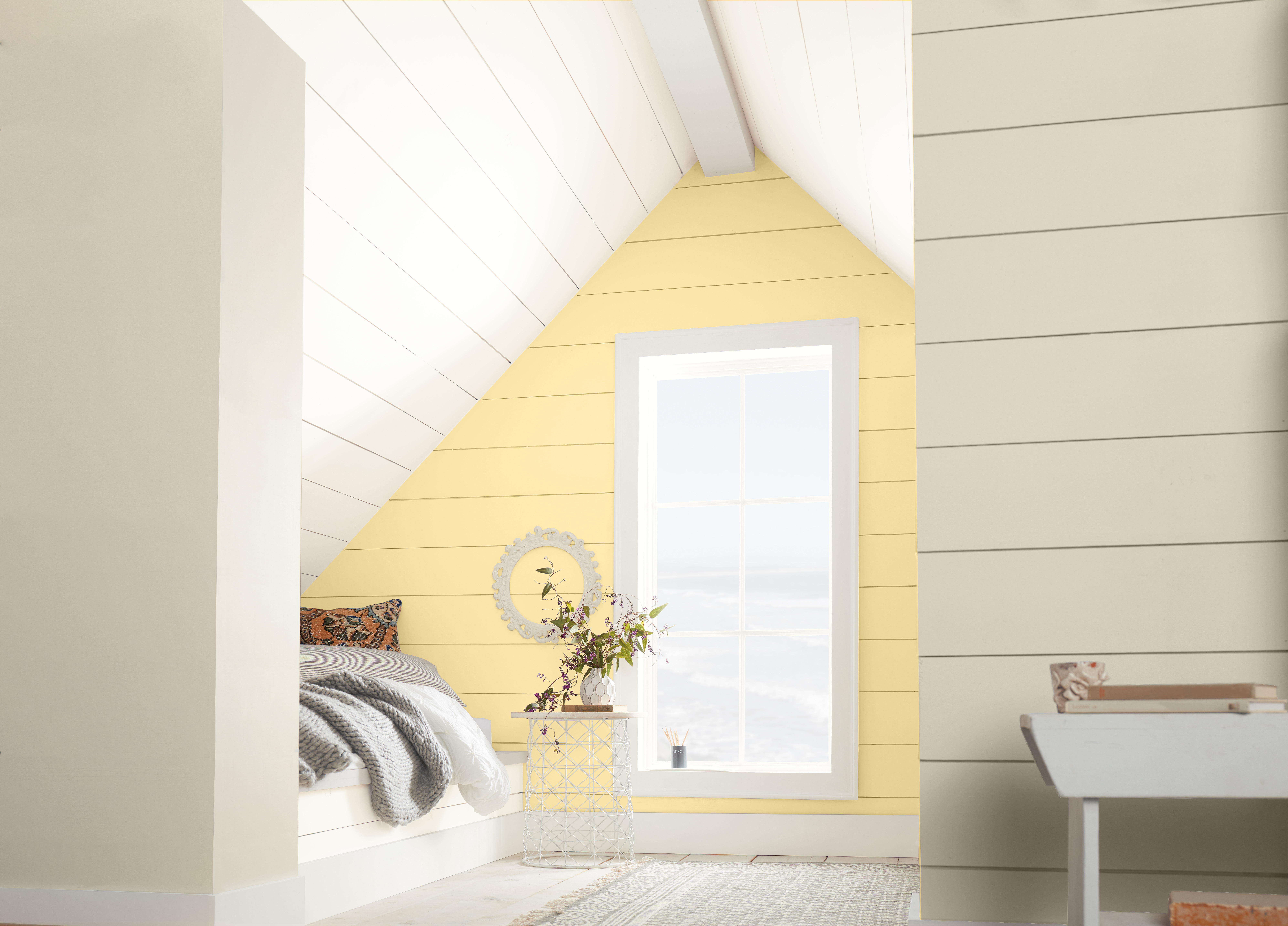 A white bedroom with an accent wall painted in a bright pastel yellow colour