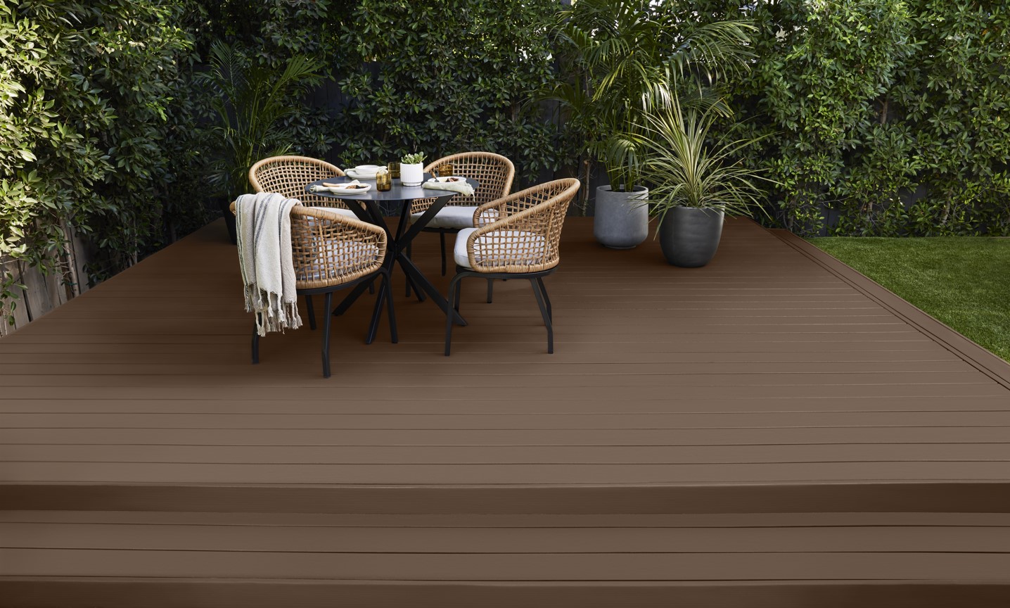 A brown solid colour wood deck with an outdoor table and chairs set
