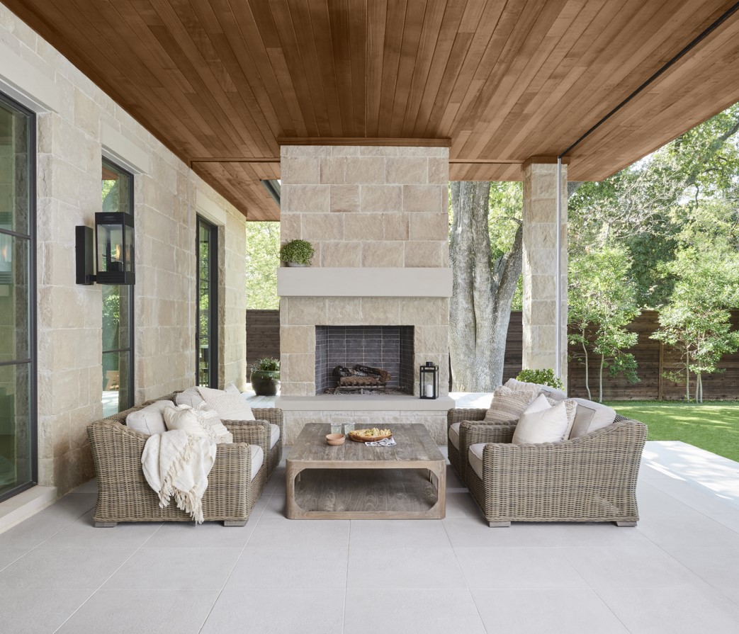 A luxurious outdoor lounge area with a fireplace and a brown semi-transparent wood ceiling