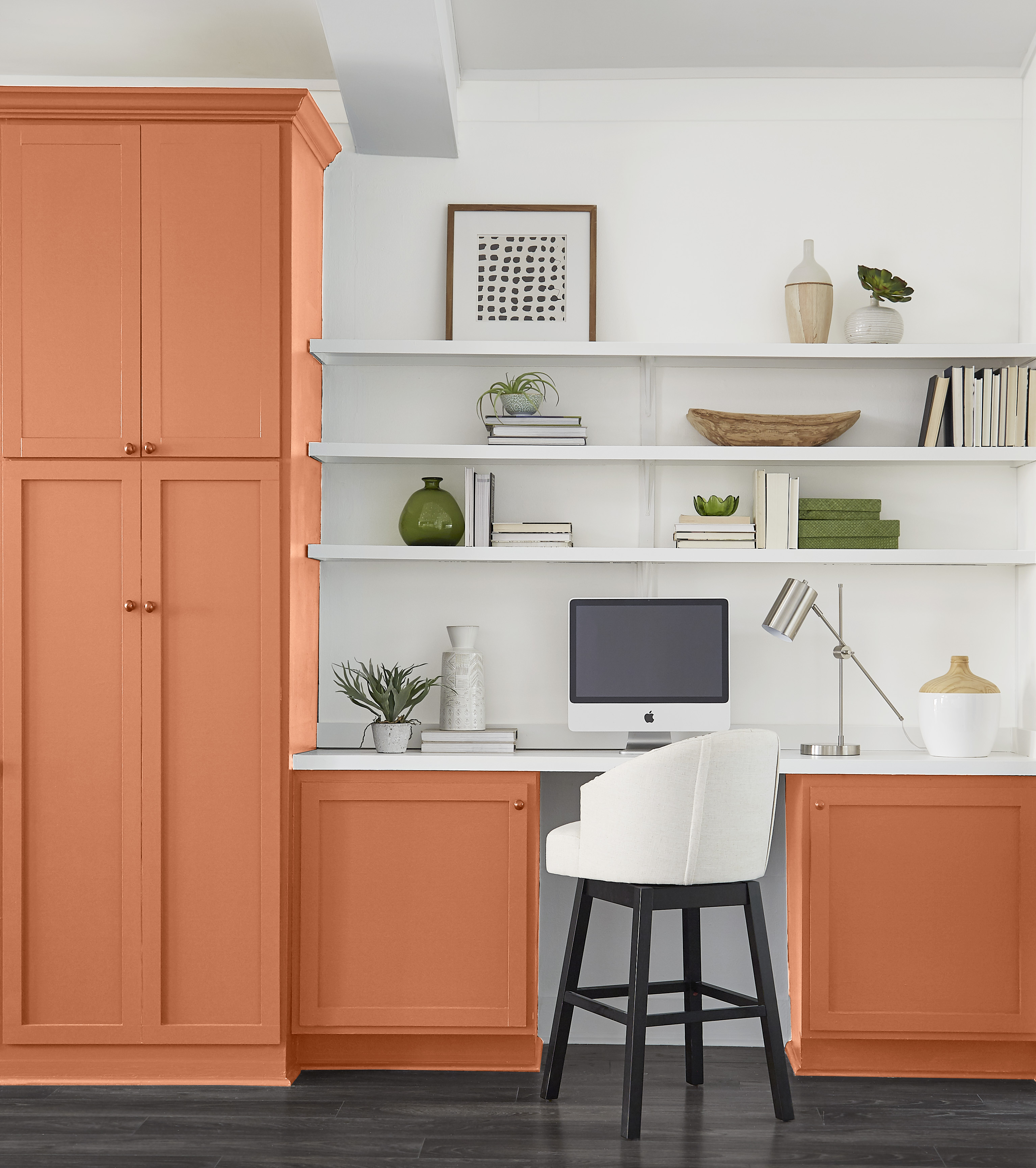 A built-in storage and desk area with cabinets painted in a dark copper-orange colour
