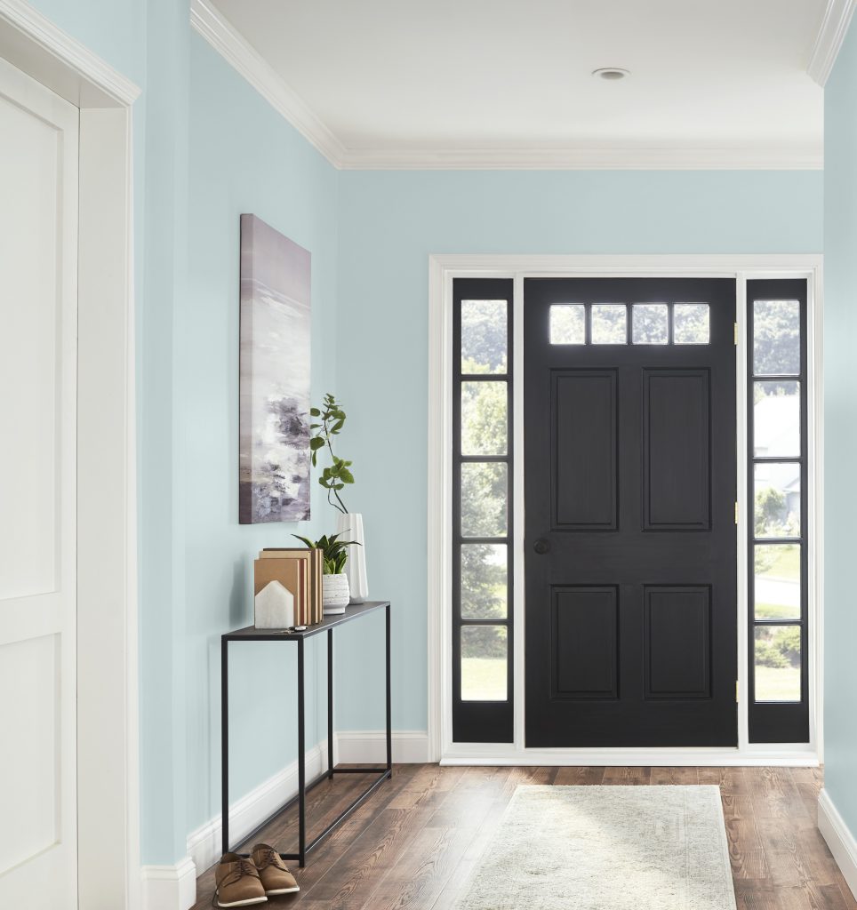 An entryway with walls painted in light blue and a contrasting front door in black 
