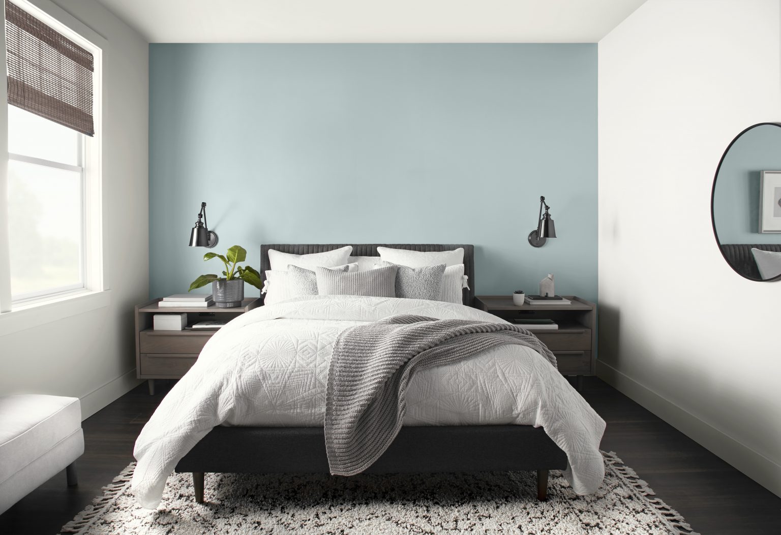 A bright white bedroom with a light blue accent wall against the bed headboard