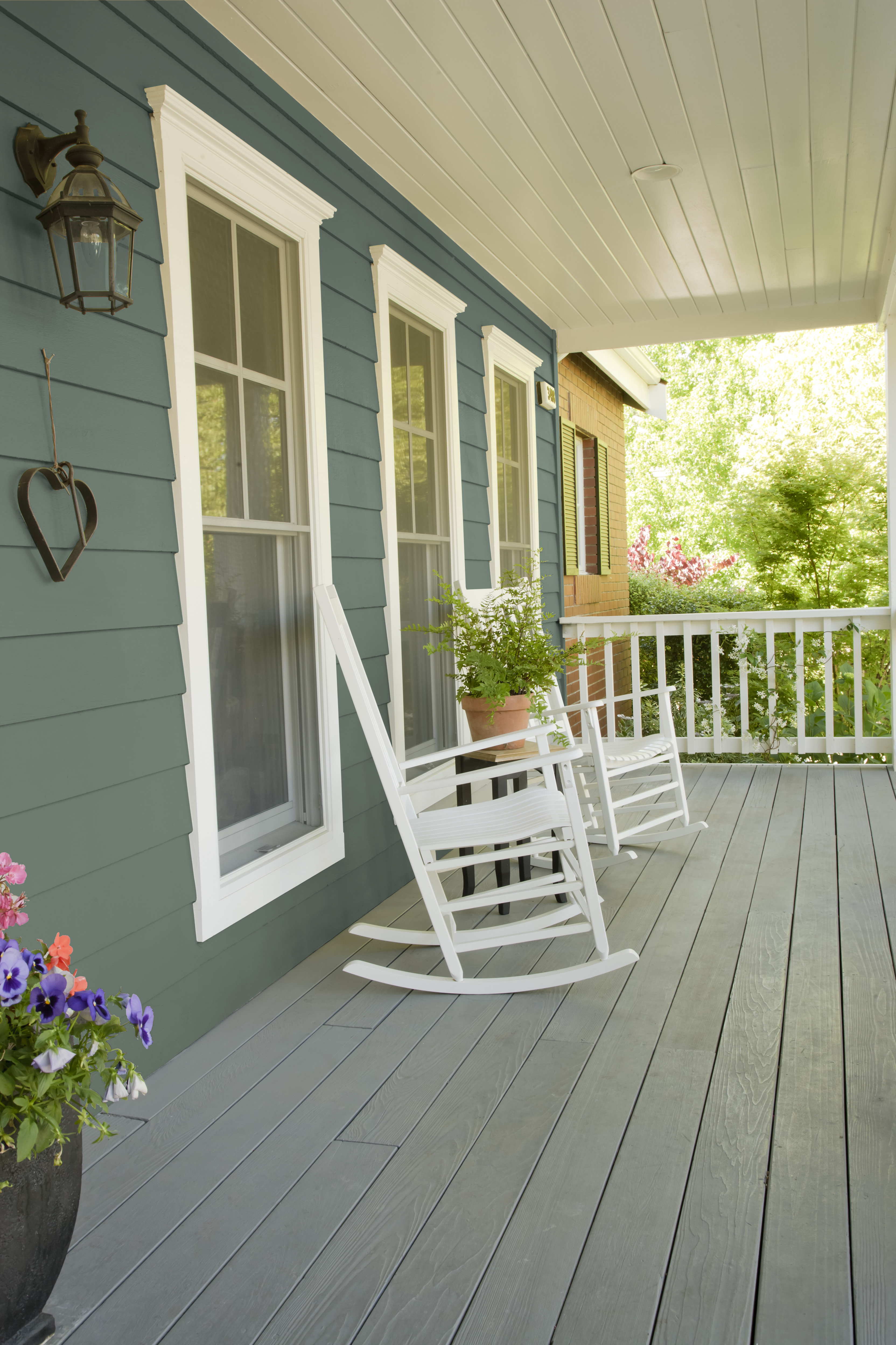 A side view of an outdoor porch area with siding painted in a deep greyish green colour