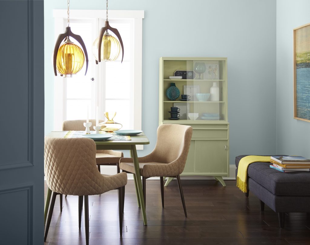 An eclectic dining room with walls painted in light blue, styled with retro décor and furniture