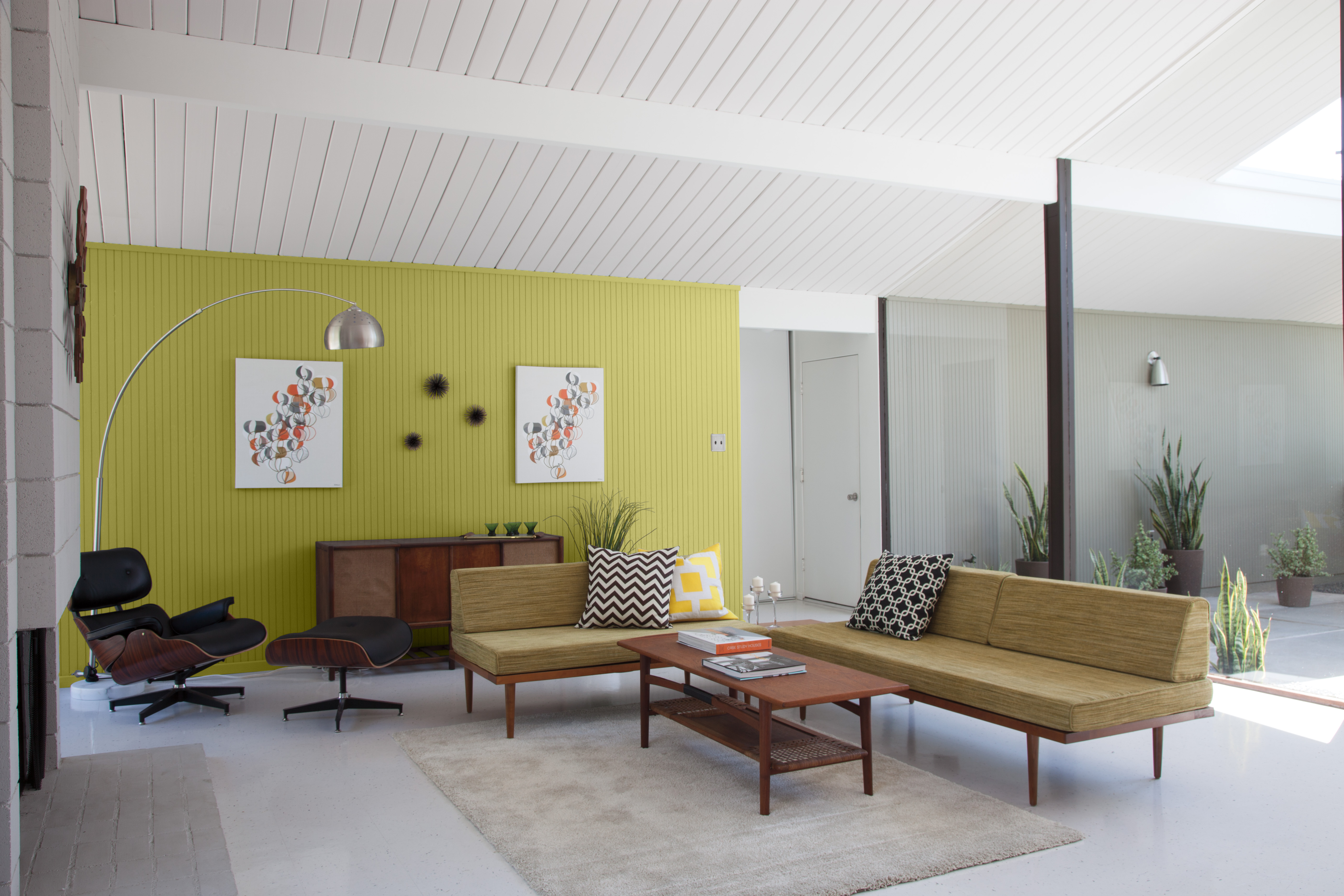 A mid-century modern living space with an accent wall painted in a vibrant green colour