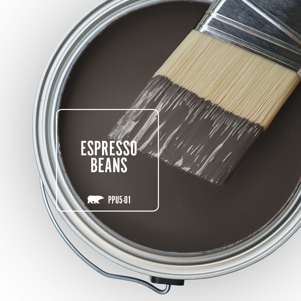 The top view of an open paint can with brown paint, there is a half-dipped paint brush leaning on top of the can.