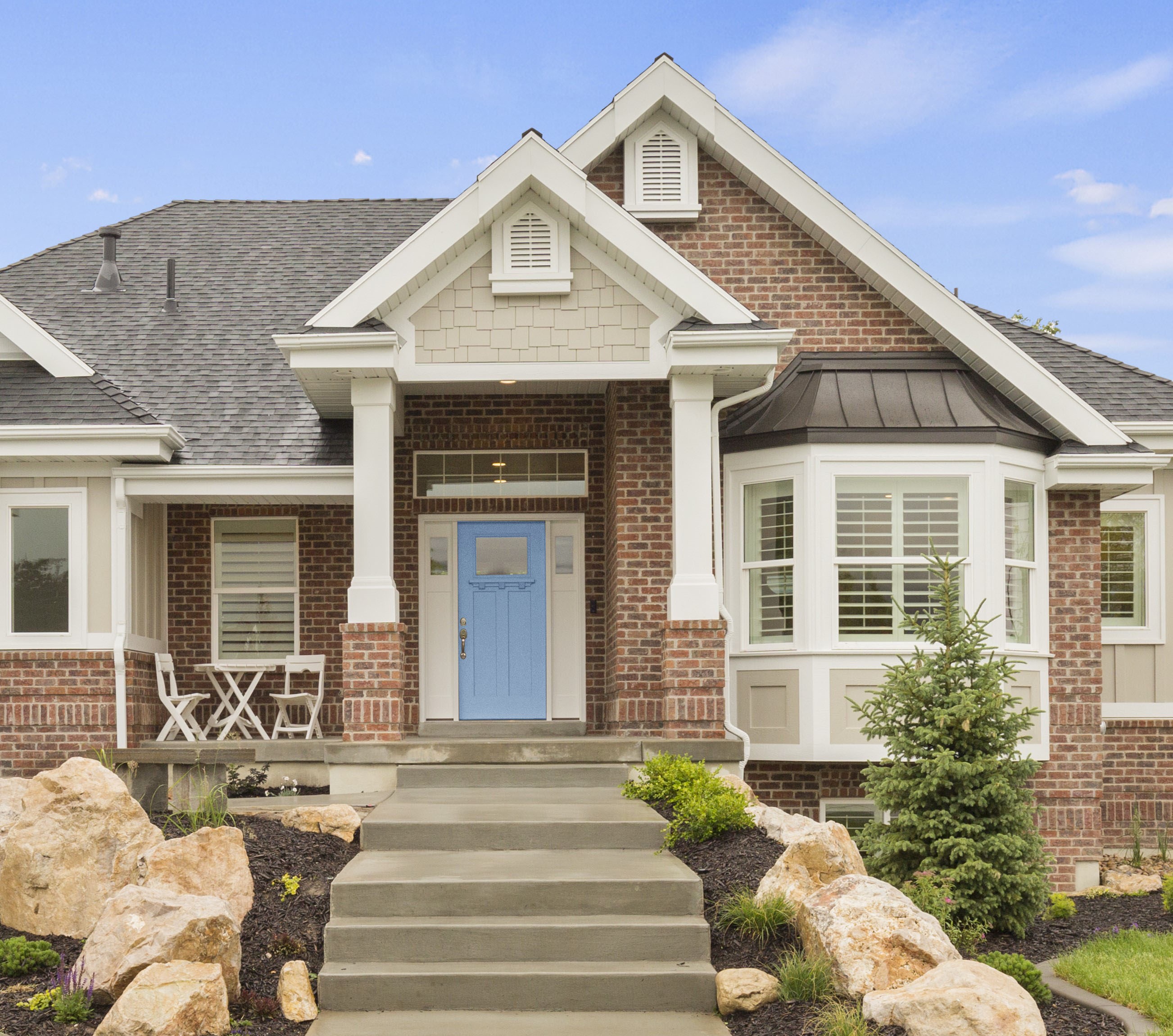 A red brick house with large windows and a striking blue front door, adding a fresh and fun touch to the traditional exterior, creating a bold and inviting entrance.